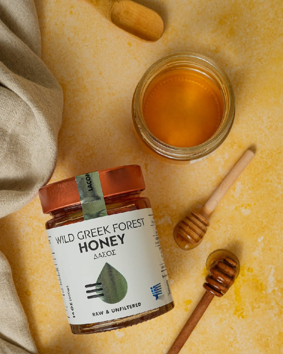 Laconic Wild Greek Forest Honey with dipper and open jar on rustic counter