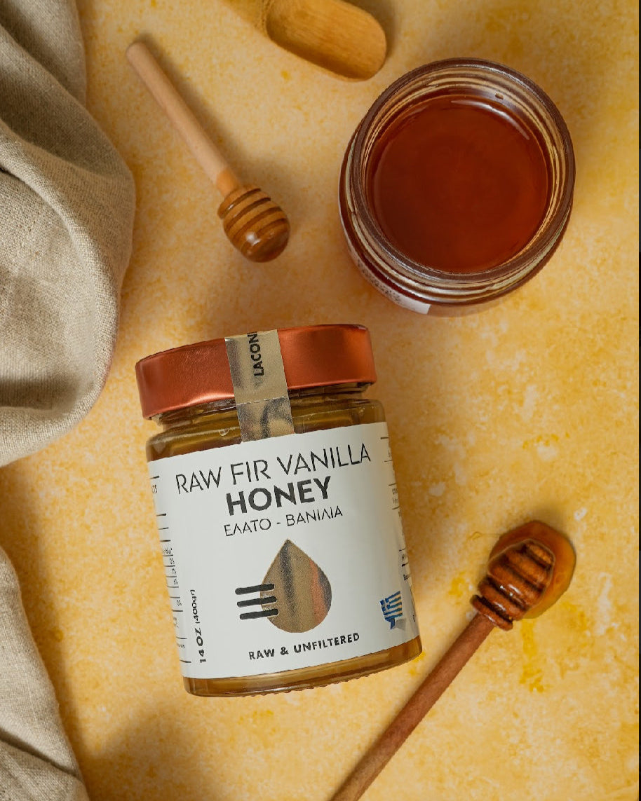 Flat lay of Raw Fir Vanilla Honey with open jar, wooden dipper, and rustic background
