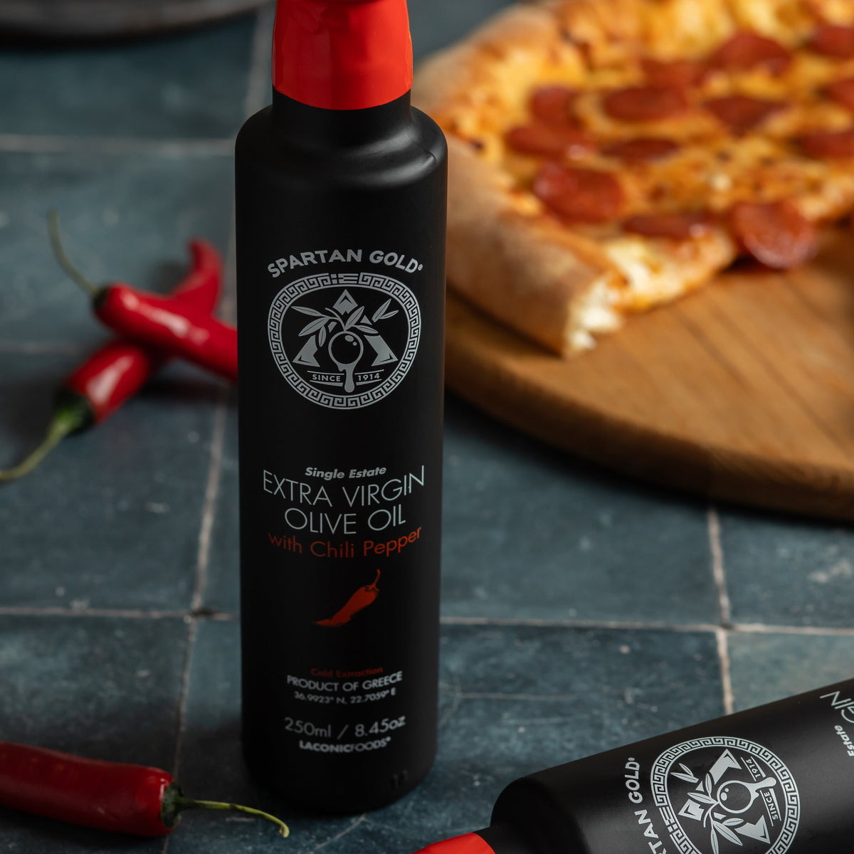 Chili Infused Extra Virgin Olive Oil bottle with pizza and fresh chili peppers