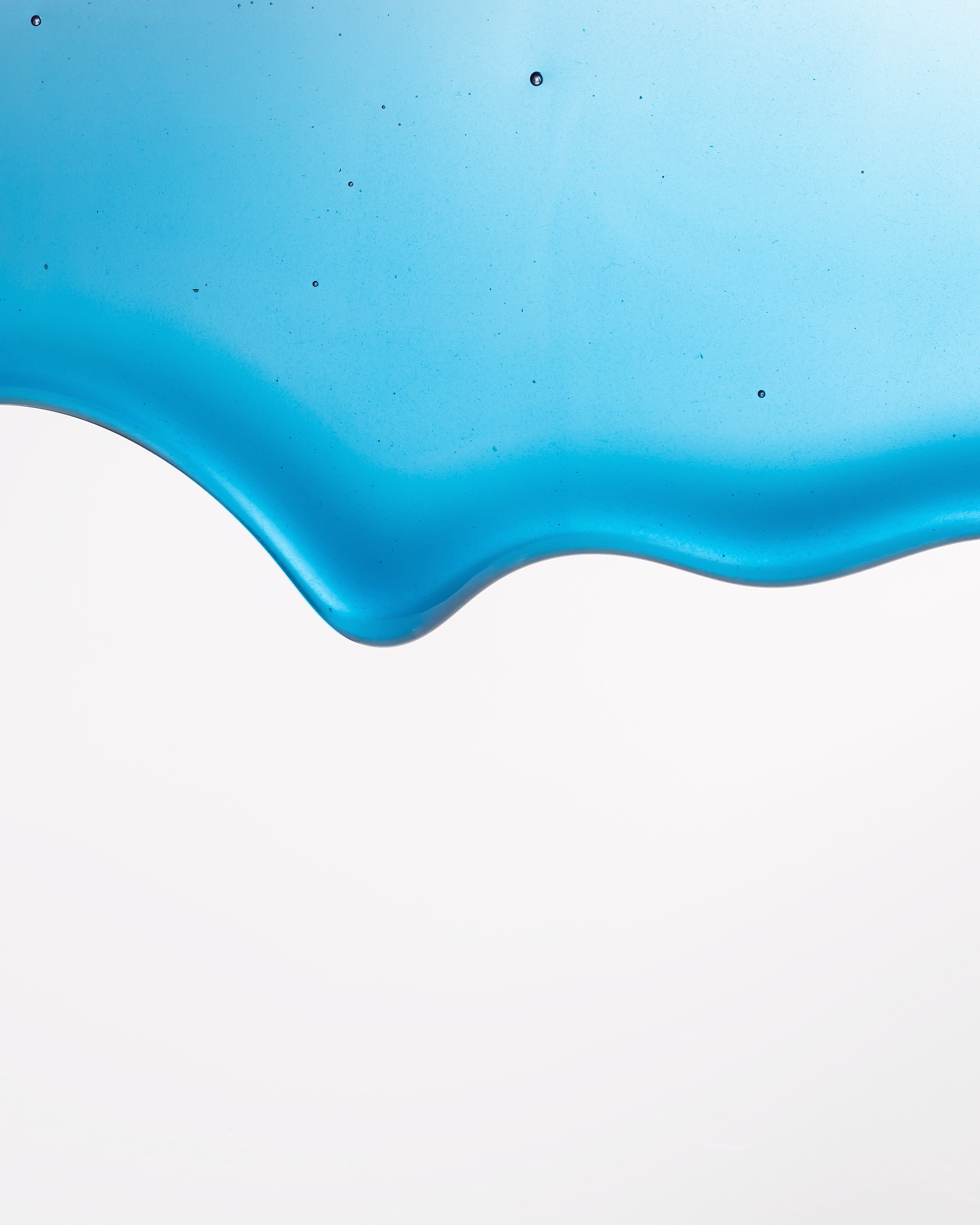 Close-up wave of Cyano blue honey with spirulina showing its natural vibrant azure color and glossy texture.