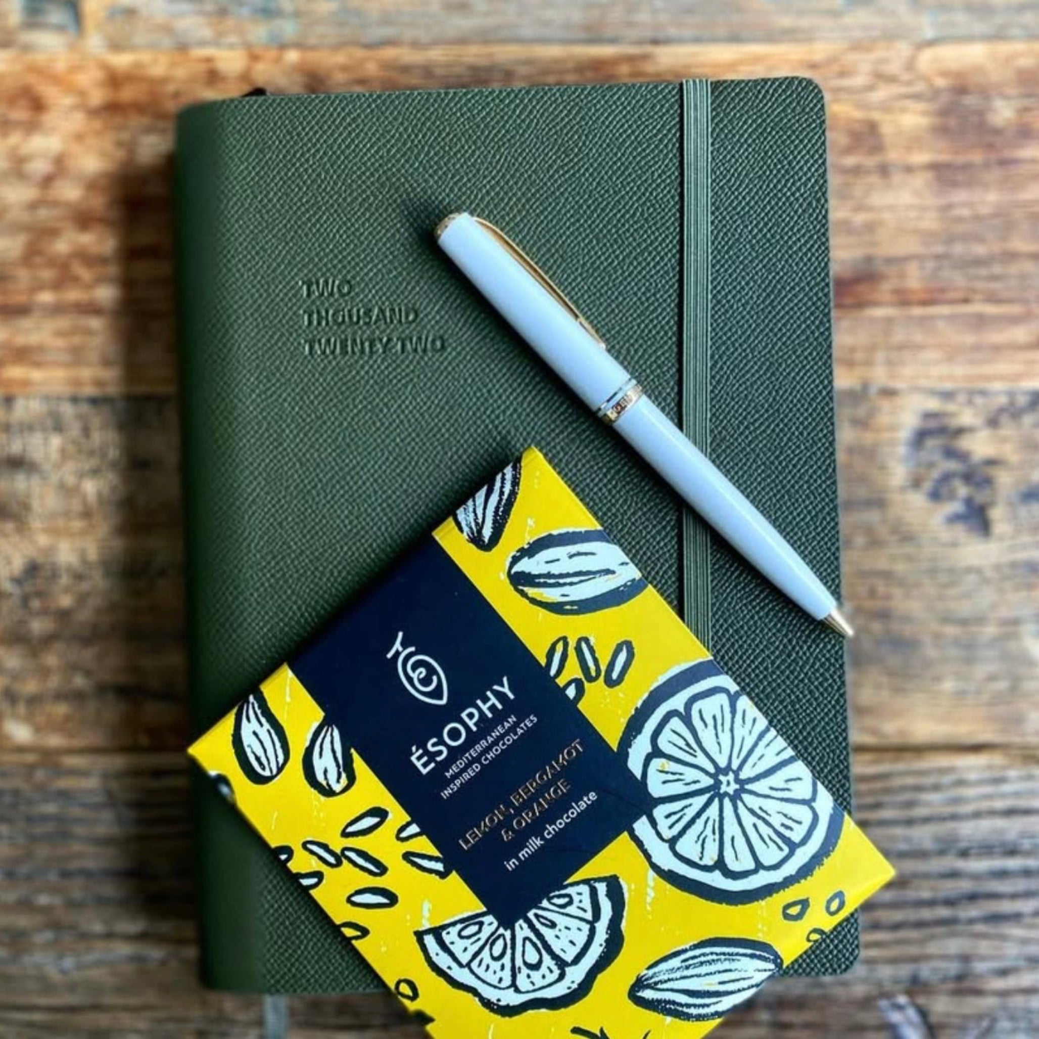 ÉSOPHY Lemon Bergamot and Orange milk chocolate bar displayed with notebook and pen on a wooden table