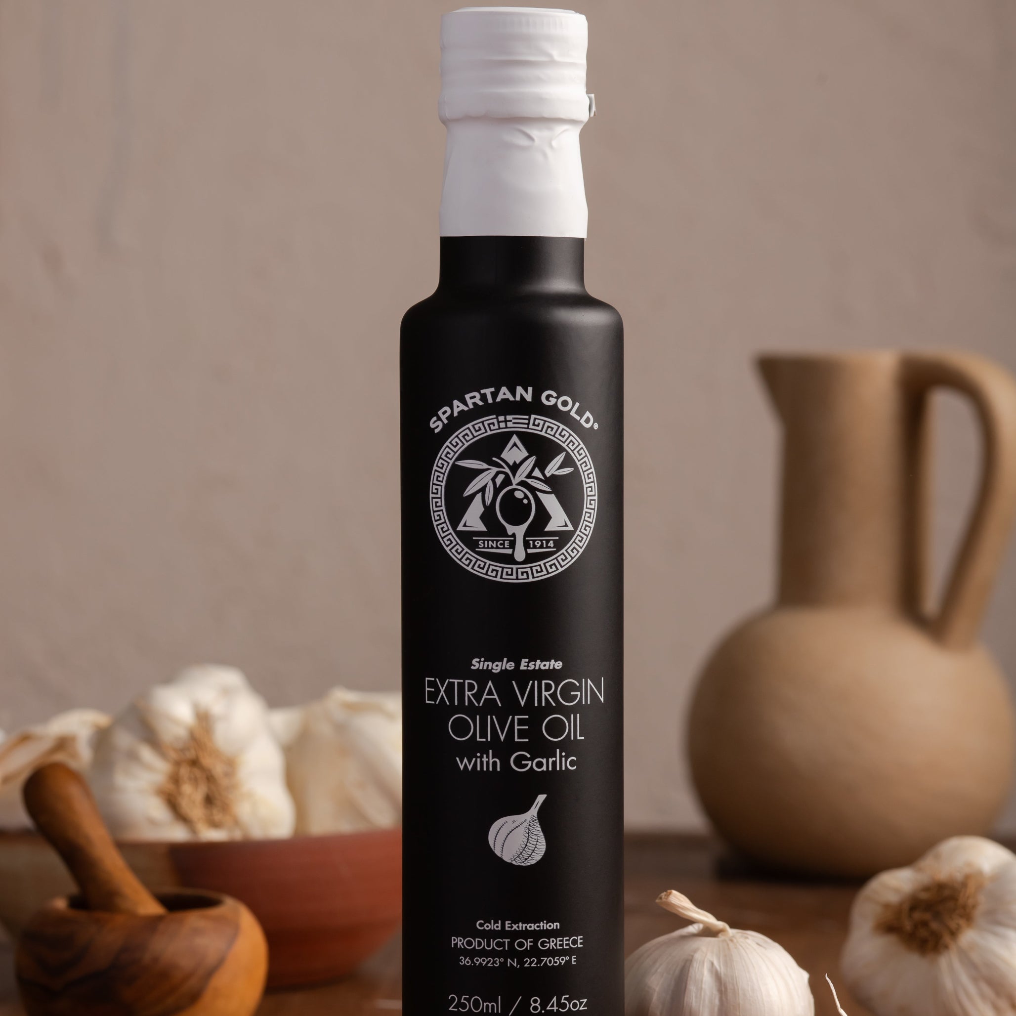 Garlic Infused EVOO bottle on wooden board surrounded by fresh garlic bulbs