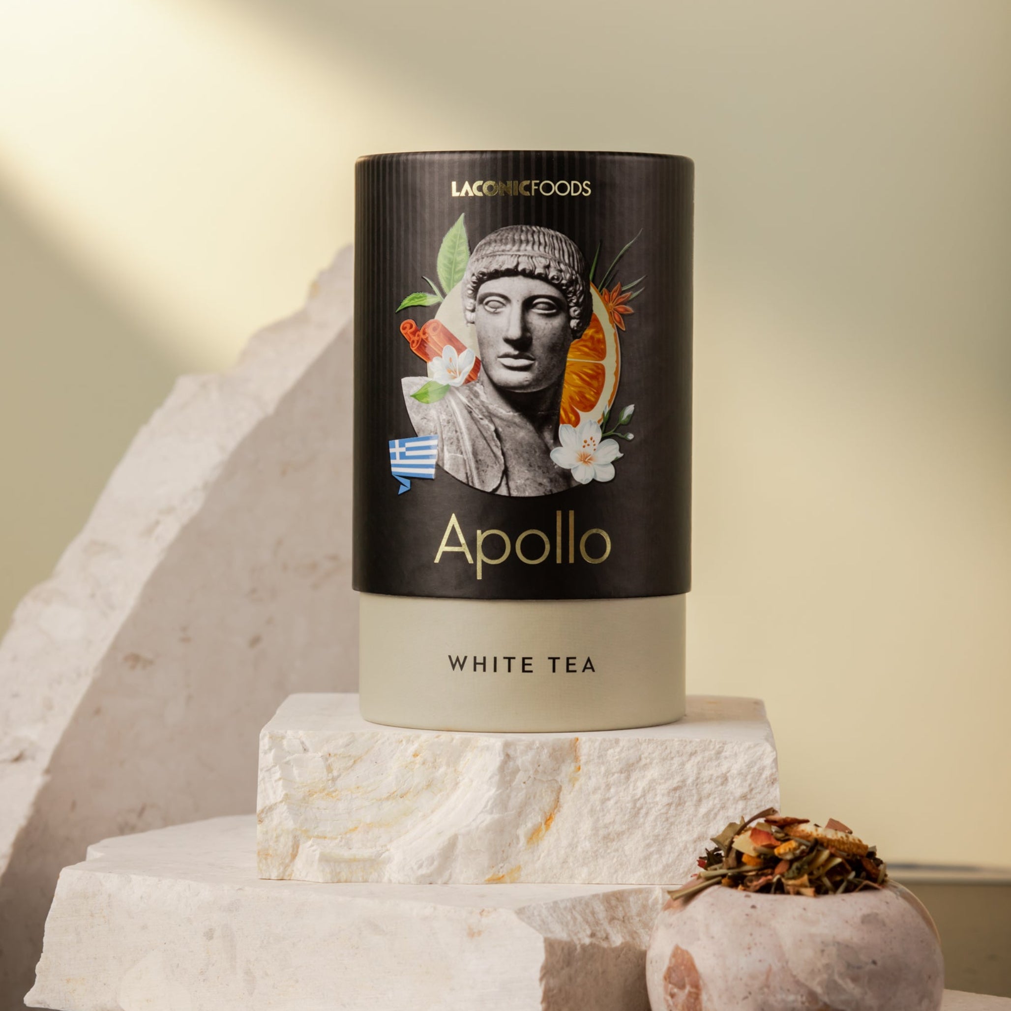 Front view of Laconic Foods Apollo White Tea canister β premium Greek loose leaf white tea styled on marble stones with warm sunlight.