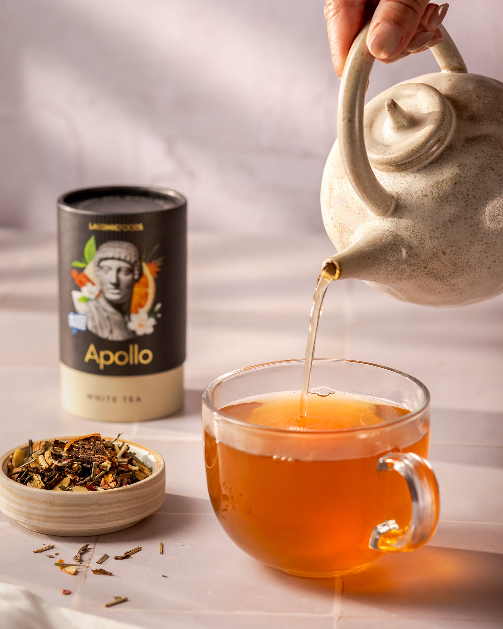 Laconic Foods Apollo White Tea poured into glass cup from ceramic teapot – Greek white tea with citrus and floral notes.