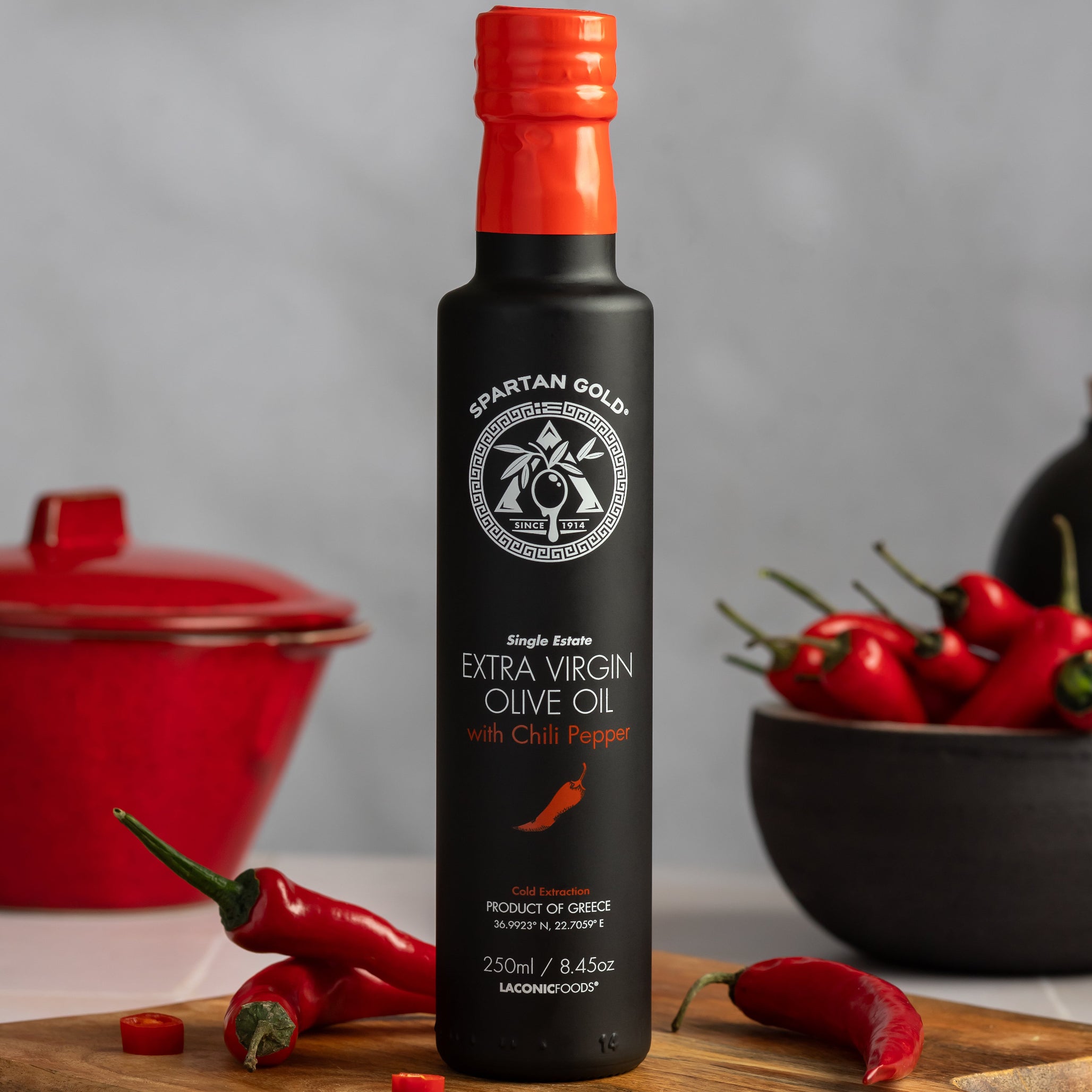 Laconic Foods Chili EVOO standing on cutting board surrounded by fresh red chilies