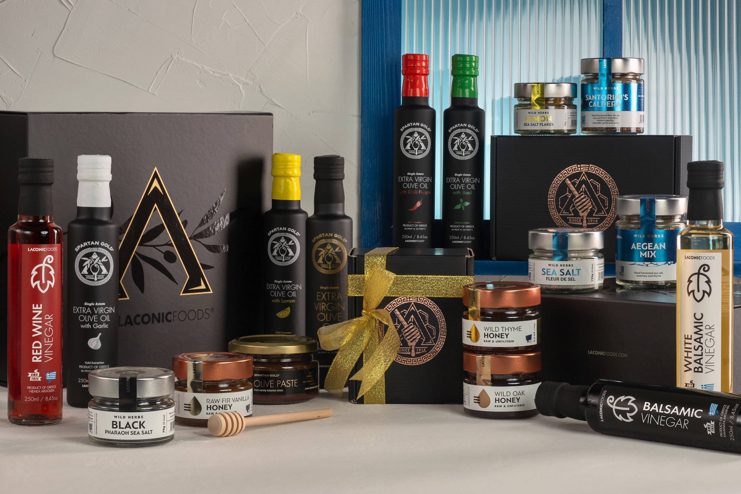 Laconic Foods premium Greek gourmet collection featuring extra virgin olive oil, raw honey, sea salt, vinegars, and spice blends presented in elegant gift boxes.
