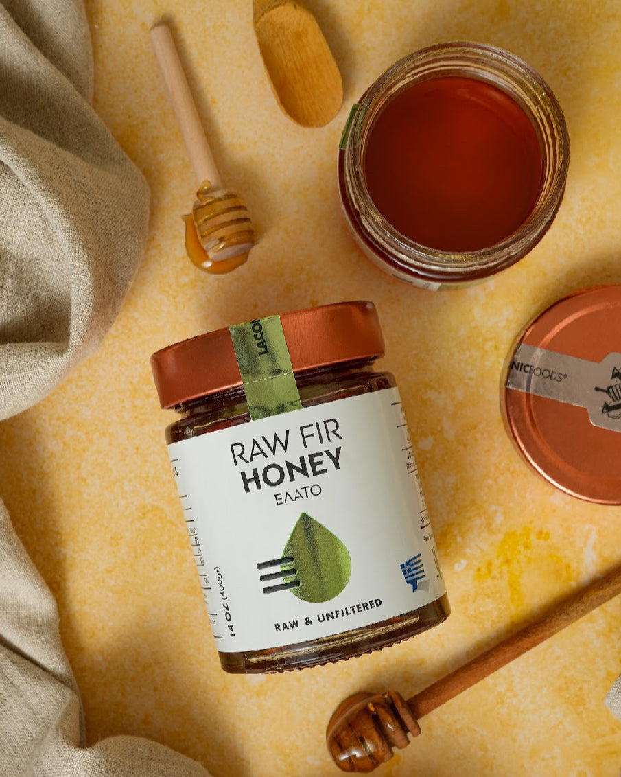 Greek Raw Fir Honey with wooden dipper and open jar on rustic background