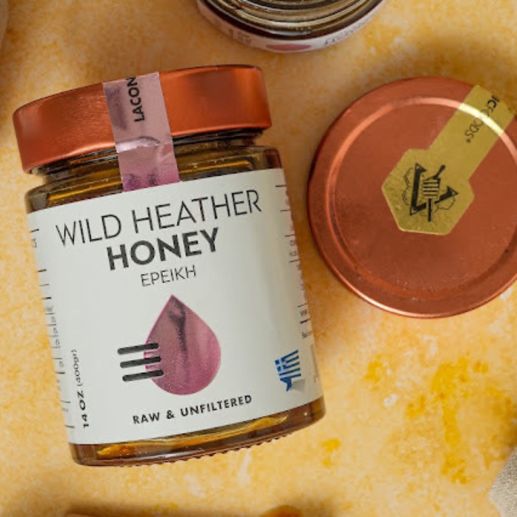 Wild Heather Honey from Greece shown in 400g jar with copper lid, rustic table setting