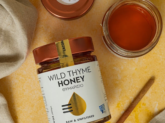 Laconic Wild Thyme Honey – Open Jar with Golden Lid on Yellow Background
