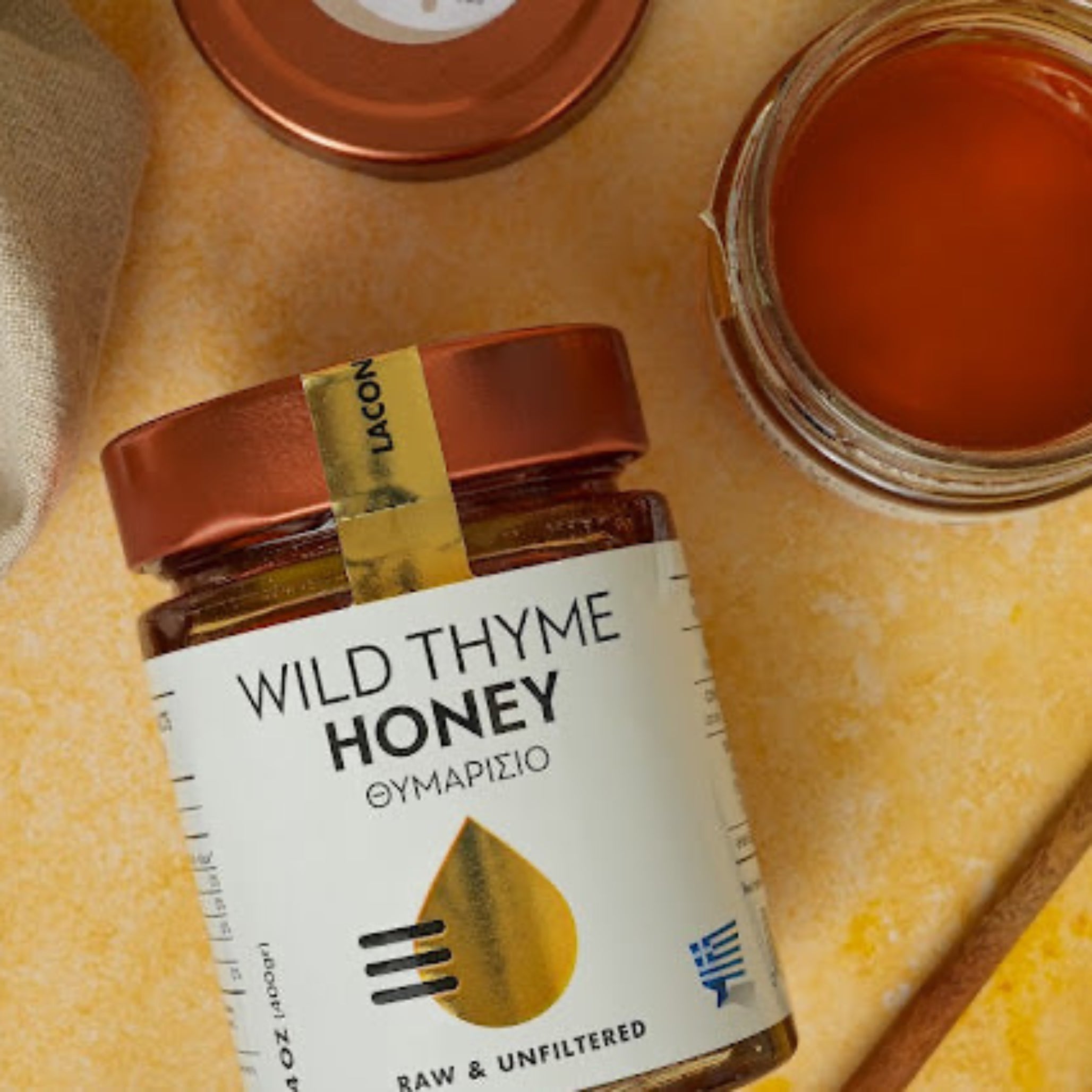 Laconic Wild Thyme Honey – Open Jar with Golden Lid on Yellow Background