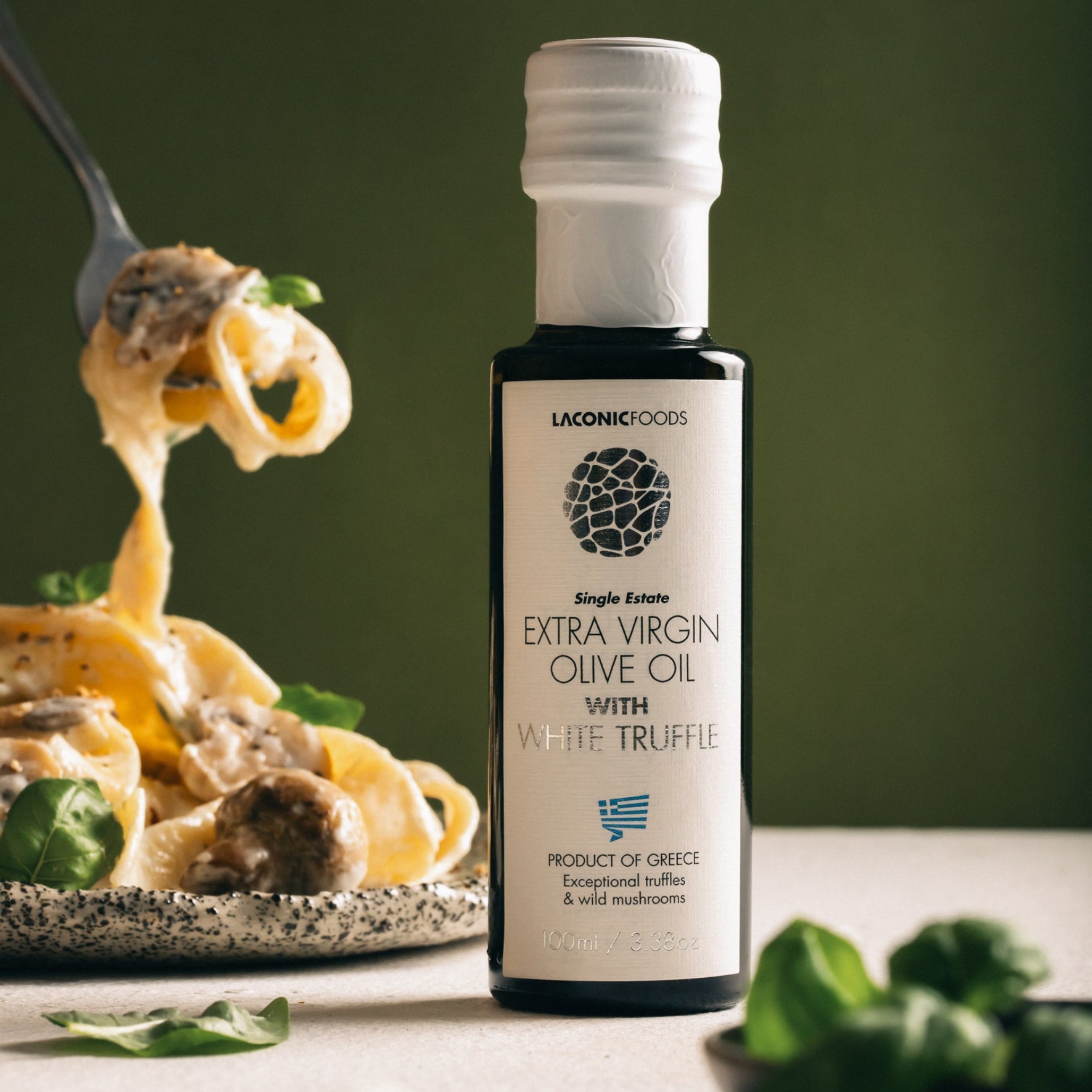Laconic Foods Extra Virgin Olive Oil with White Truffle next to creamy tagliatelle pasta being lifted with a fork.