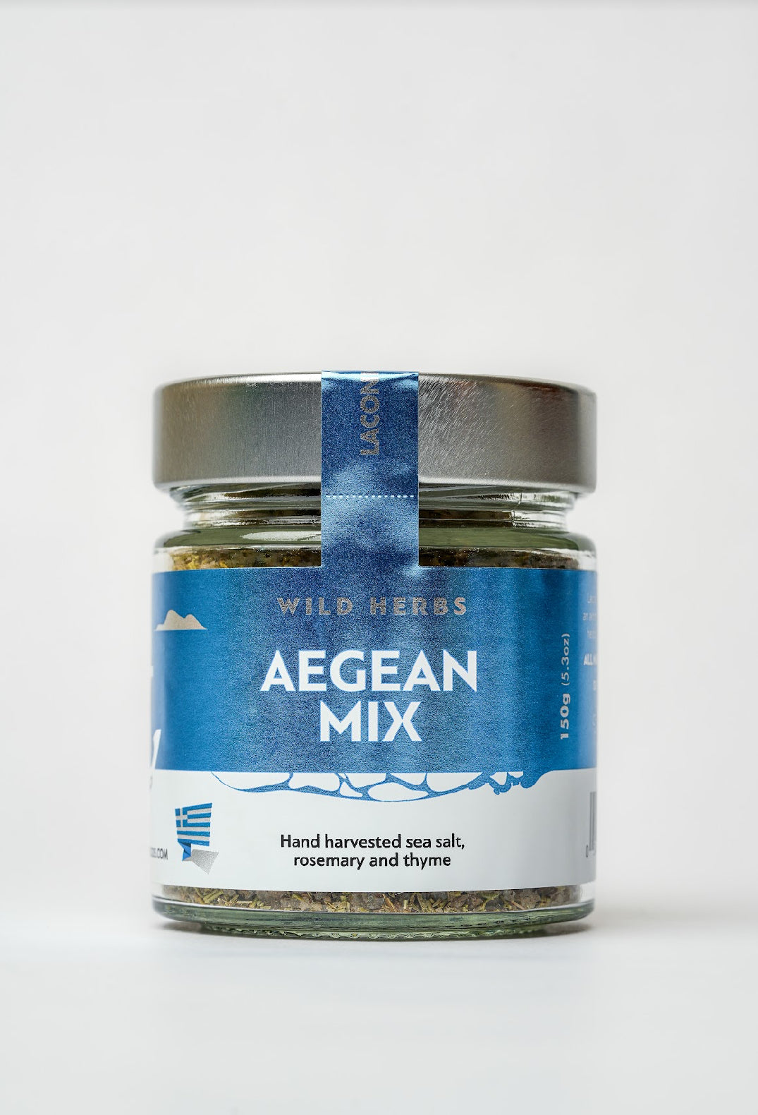 Glass jar of Aegean Mix Greek sea salt blend with wild rosemary and thyme, 150g, labeled with blue and white packaging.