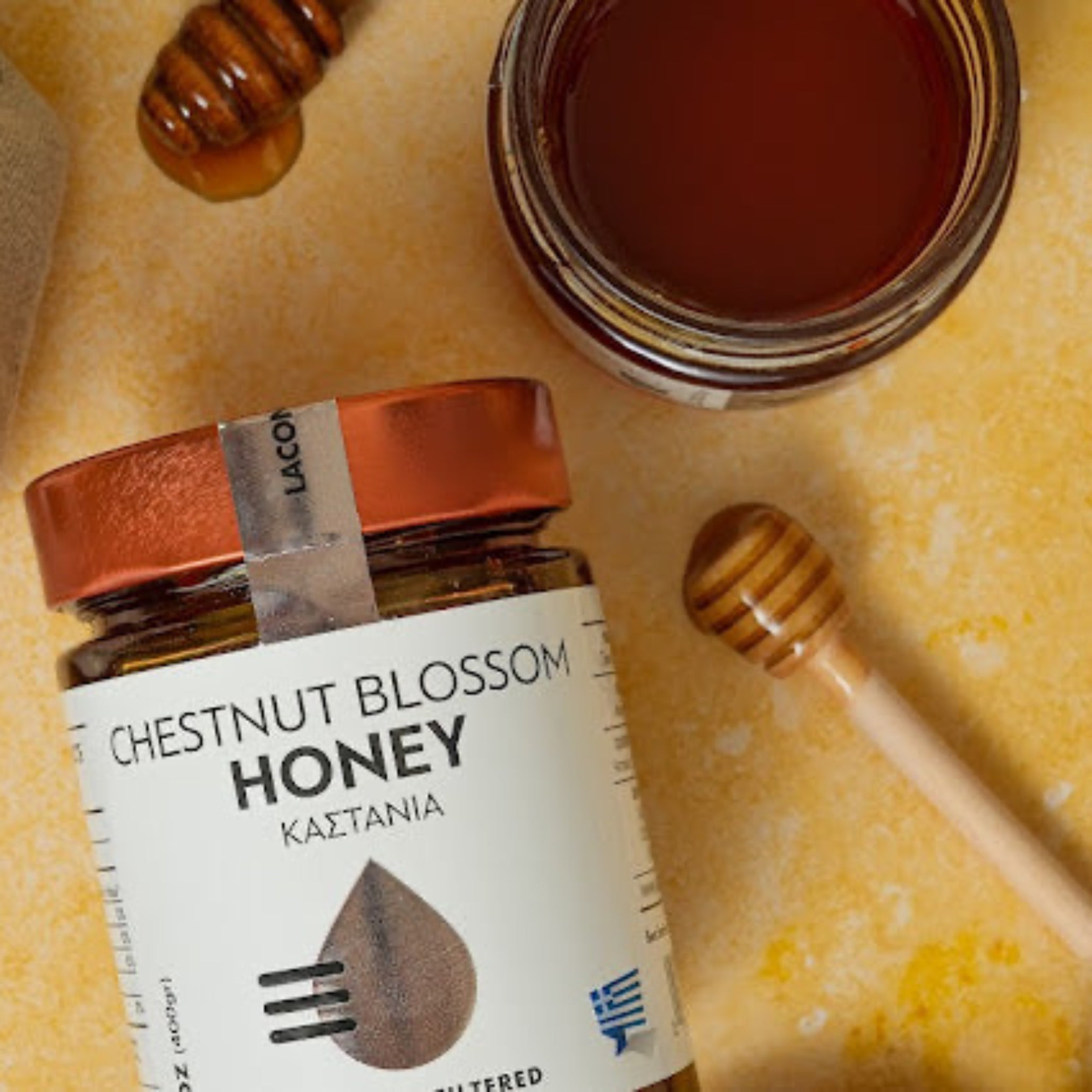 Greek Chestnut Blossom Honey jar with honey dipper and open jar on rustic background