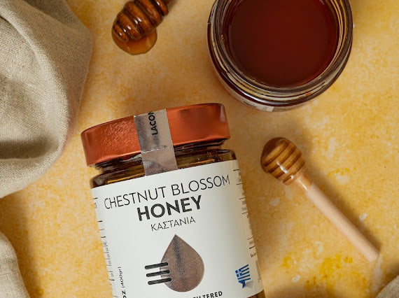 Greek Chestnut Blossom Honey jar with honey dipper and open jar on rustic background