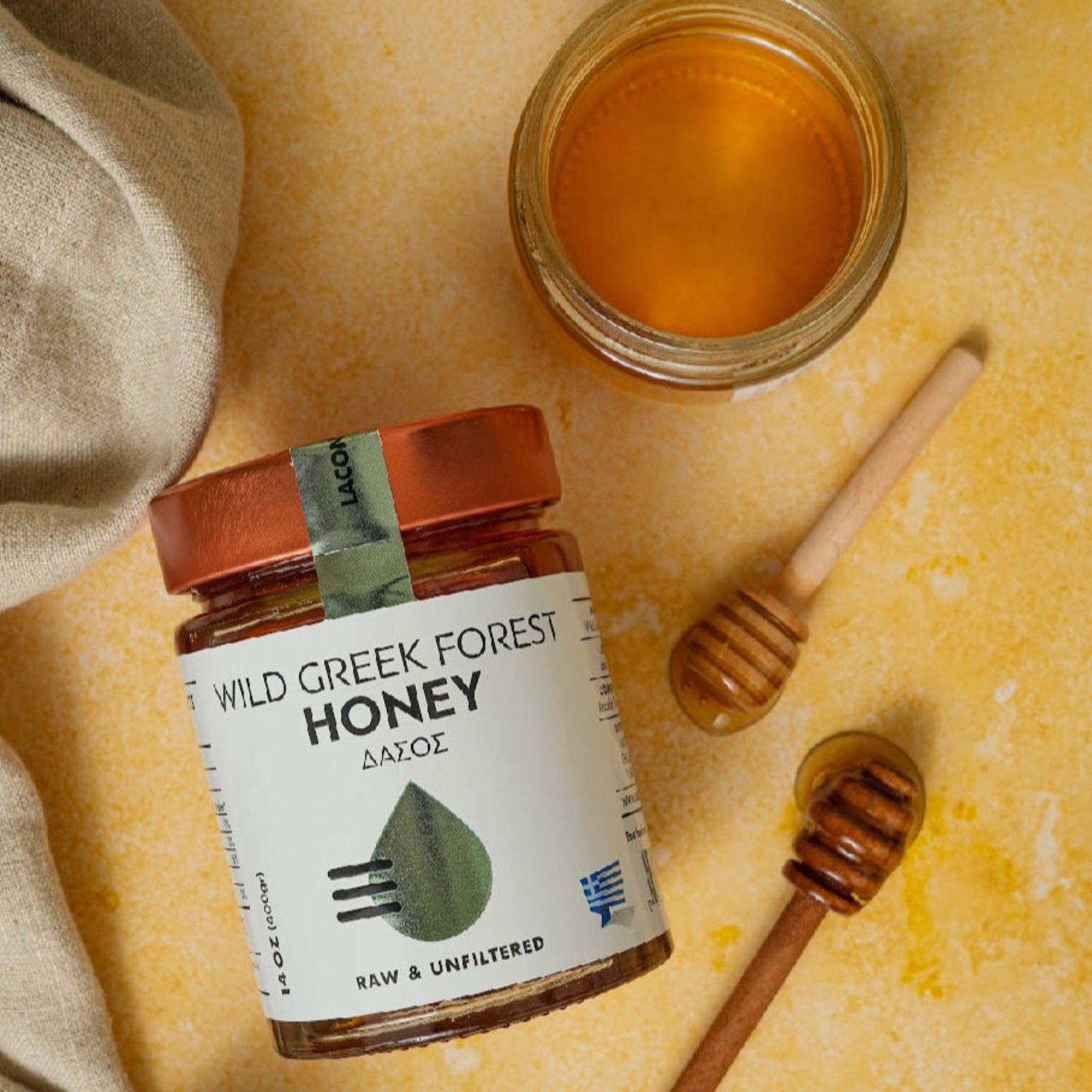 Laconic Wild Greek Forest Honey with dipper and open jar on rustic counter