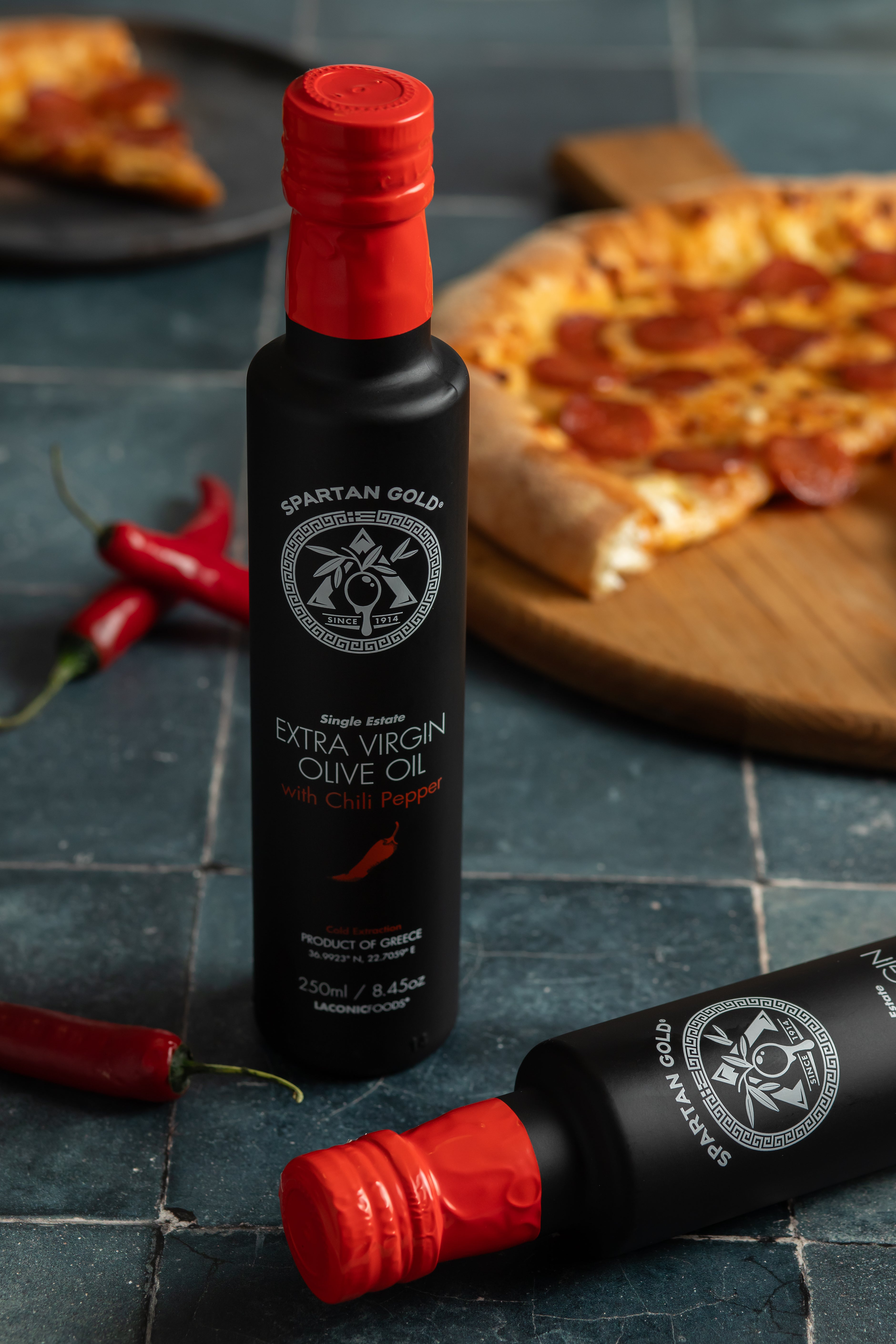 Chili Infused Extra Virgin Olive Oil bottle with pizza and fresh chili peppers