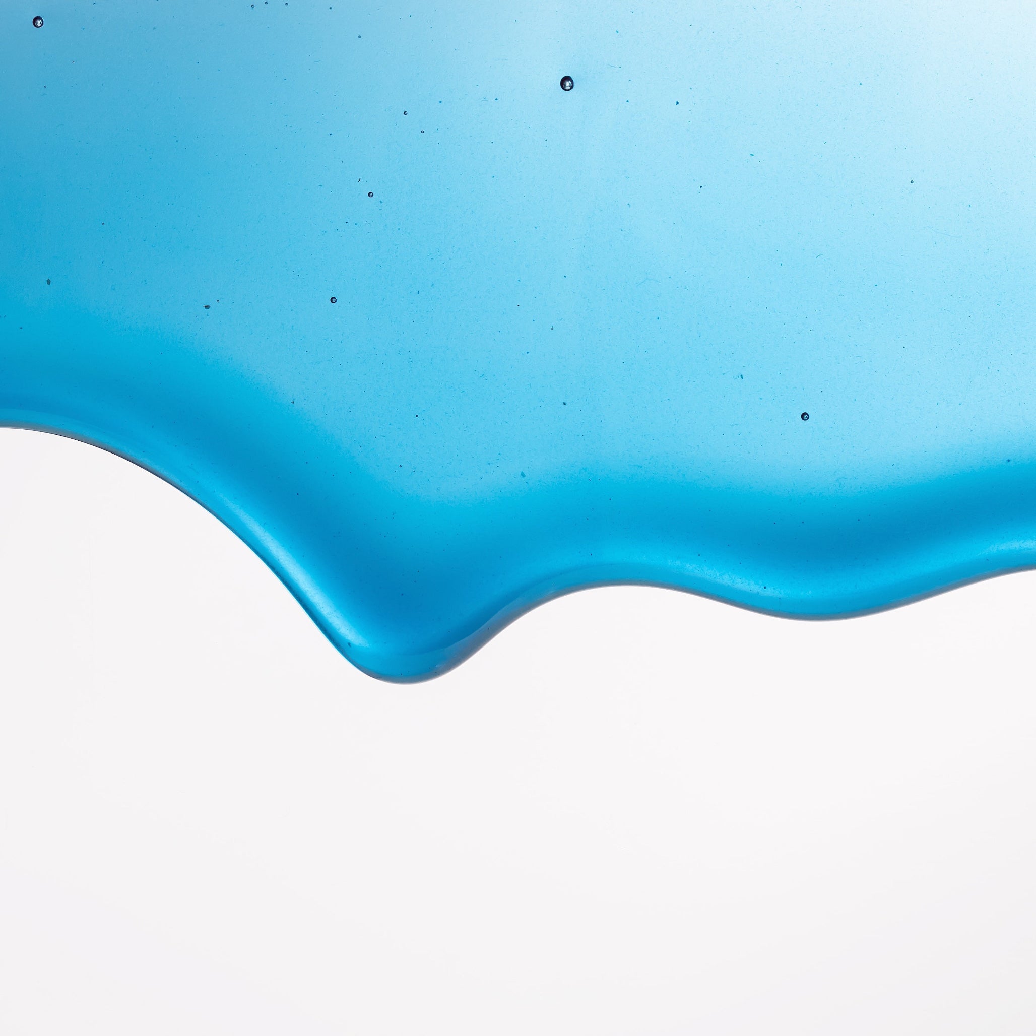 Close-up wave of Cyano blue honey with spirulina showing its natural vibrant azure color and glossy texture.