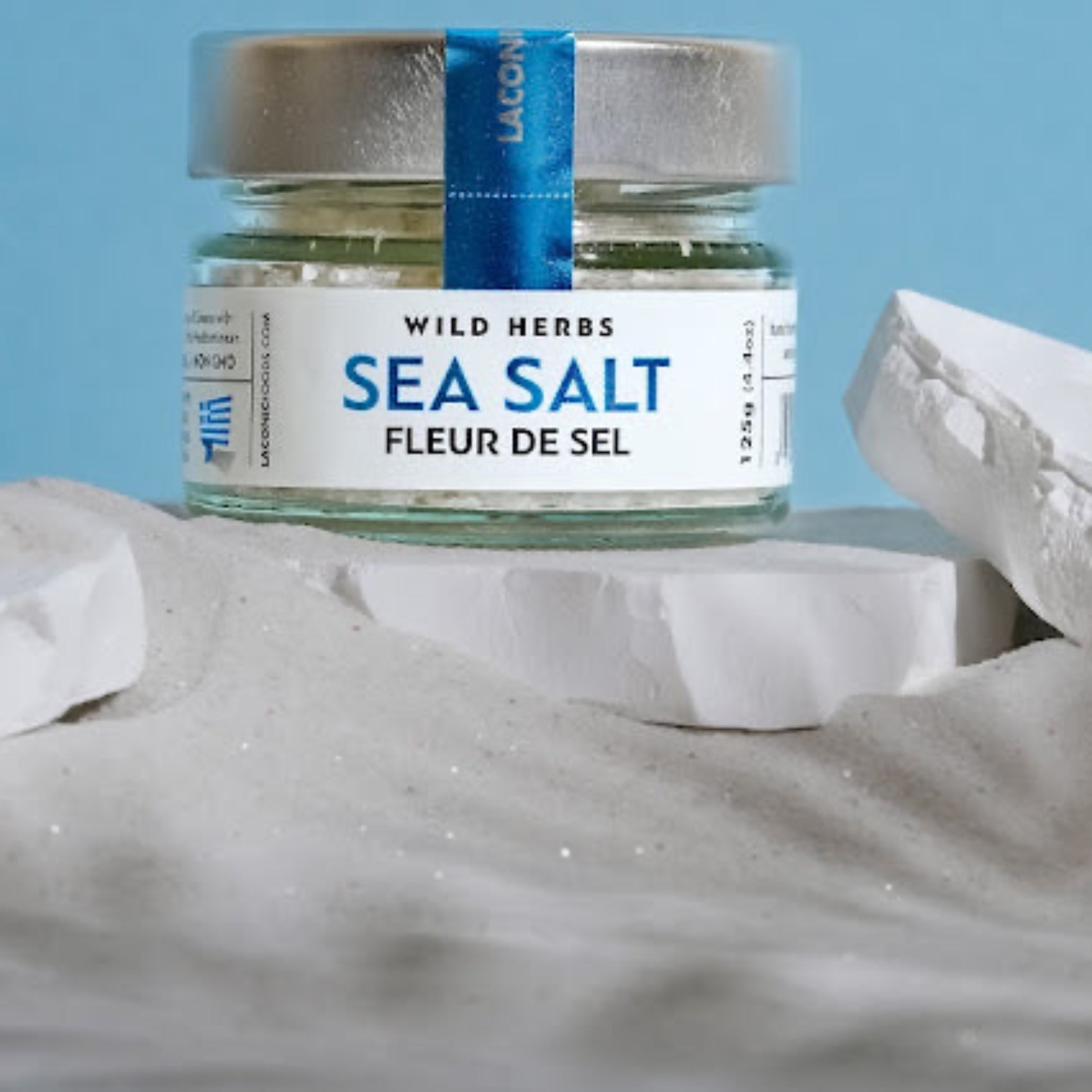 Fleur de Sel Greek sea salt by Laconic Foods on Mediterranean sand with blue background