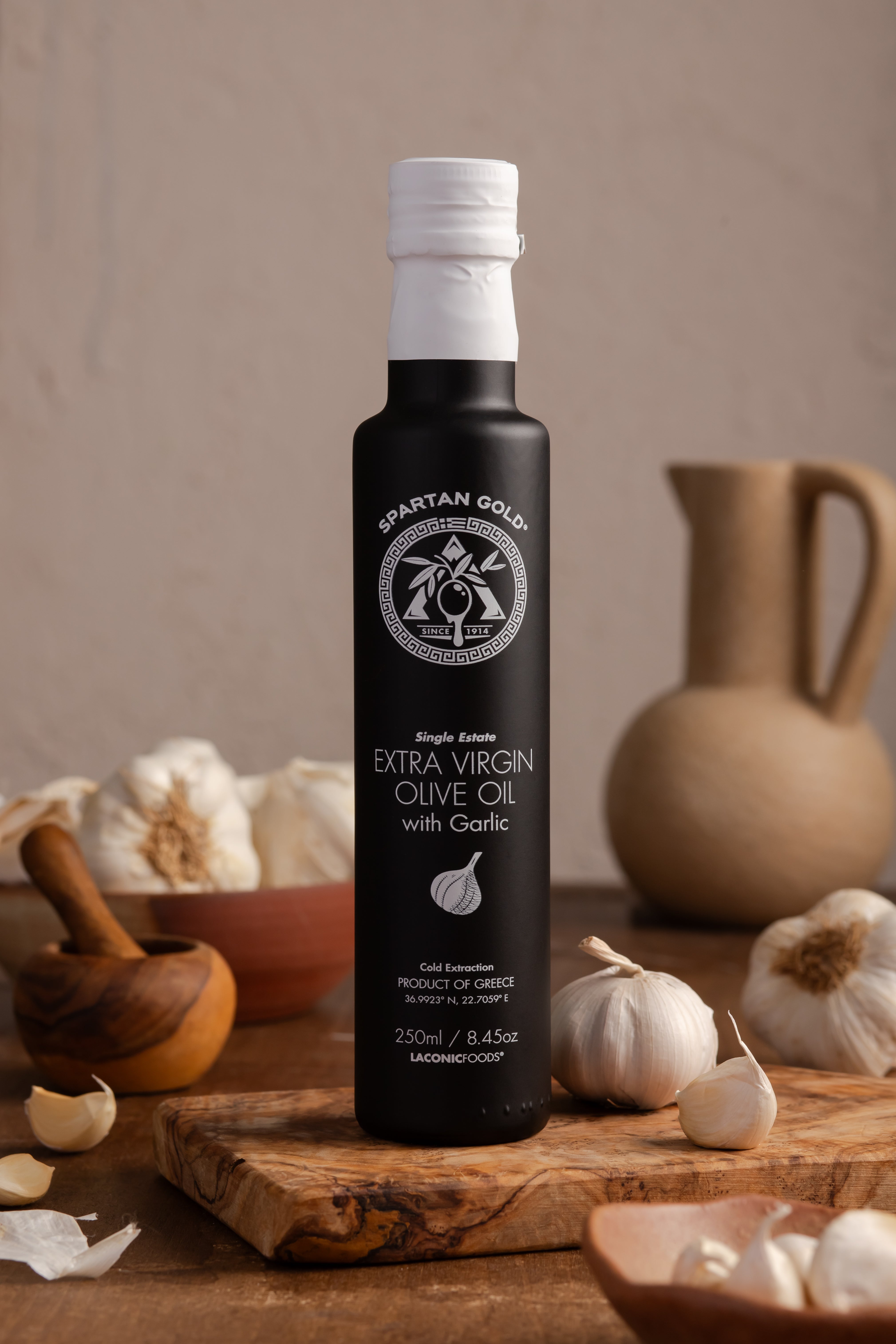Garlic Infused EVOO bottle on wooden board surrounded by fresh garlic bulbs