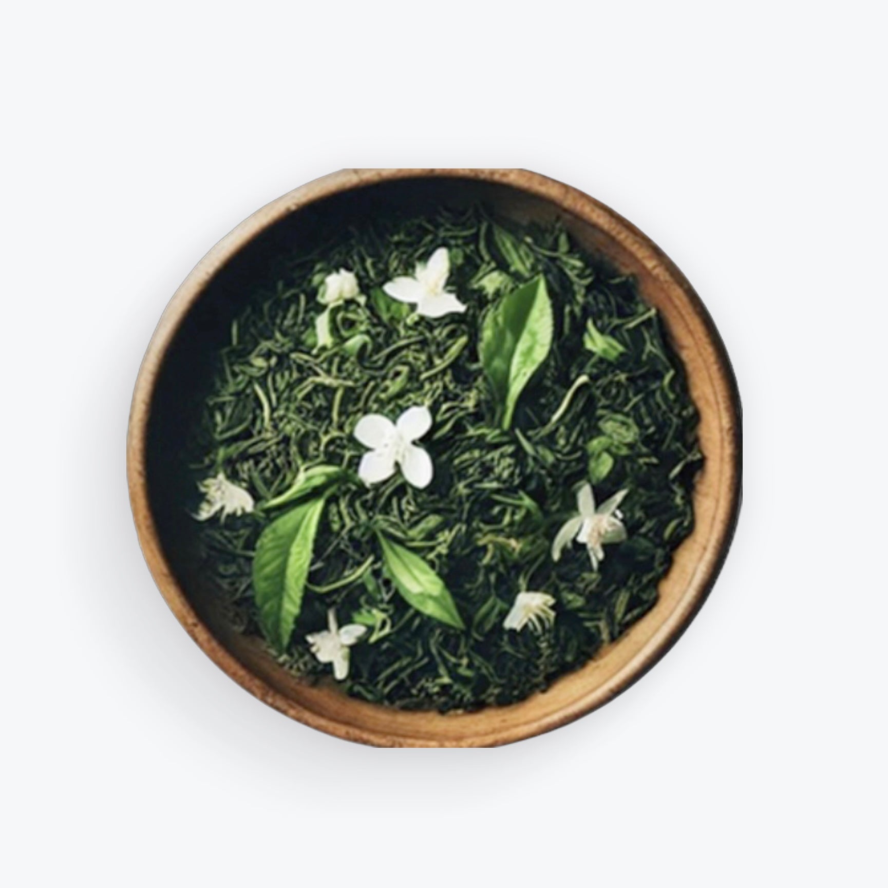 Loose leaf Jasmine green tea with jasmine blossoms in a wooden bowl