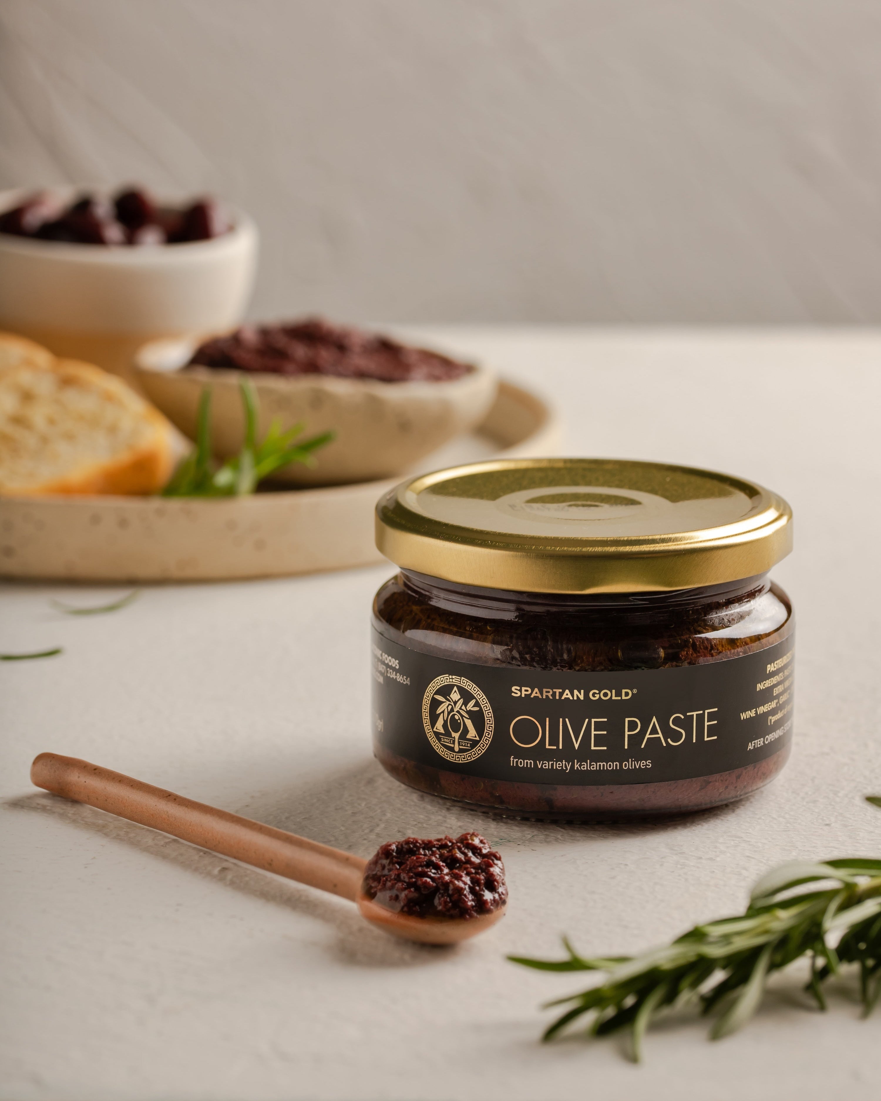 Artisan Greek Kalamata Olive Paste with olive oil, bread, and rosemary on counter