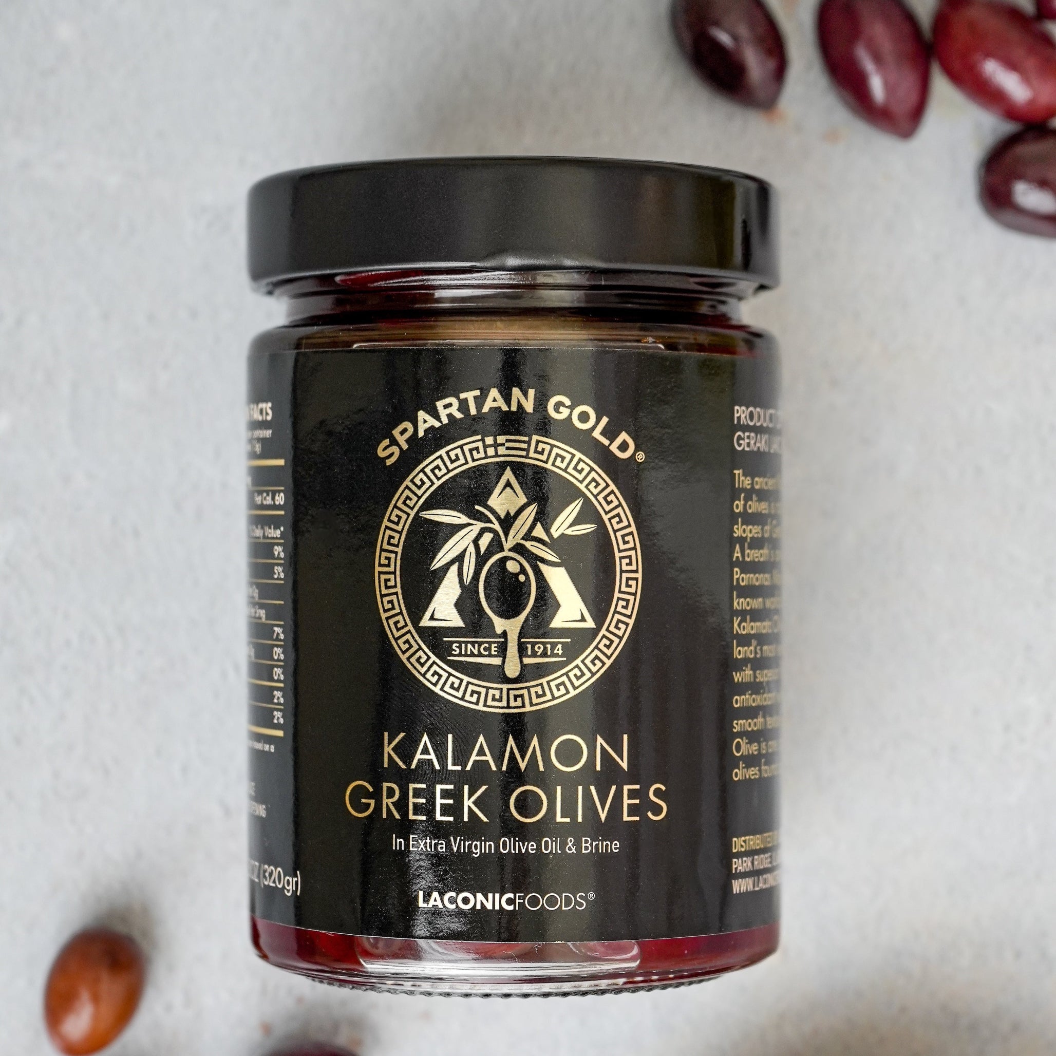 Laconic Foods Kalamon Greek Olives jar surrounded by Kalamata olives on countertop