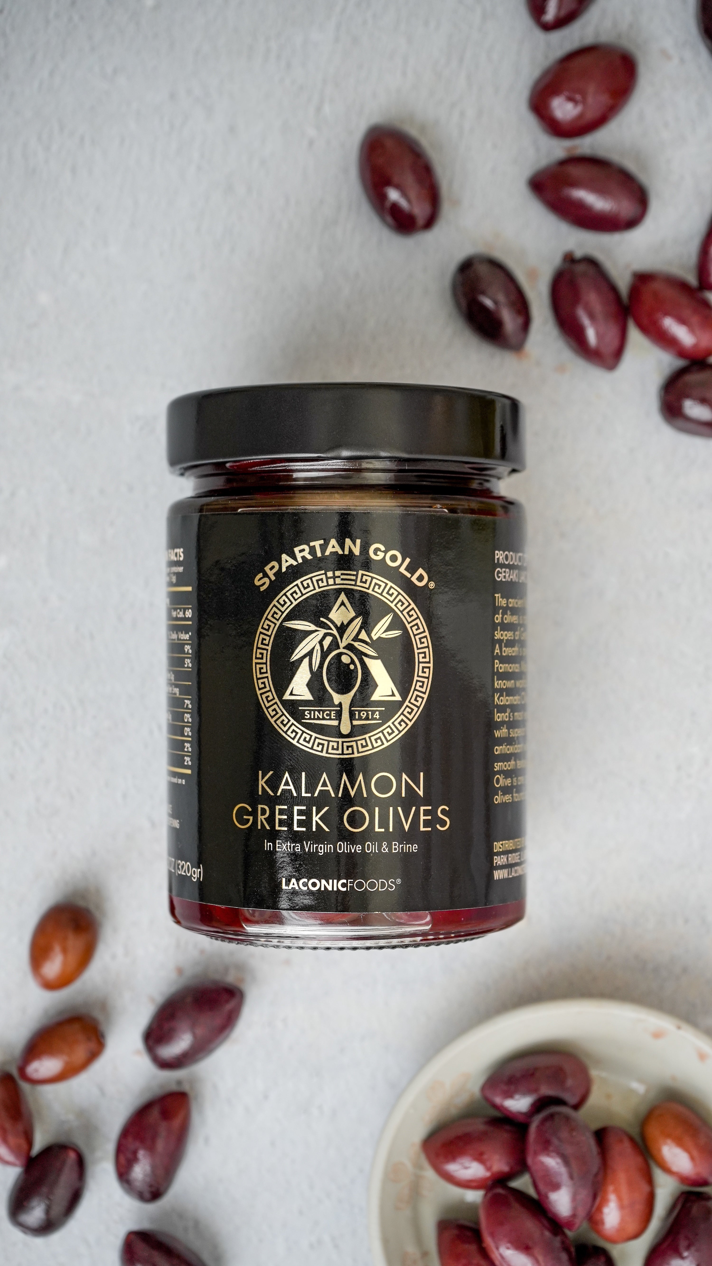 Laconic Foods Kalamon Greek Olives jar surrounded by Kalamata olives on countertop