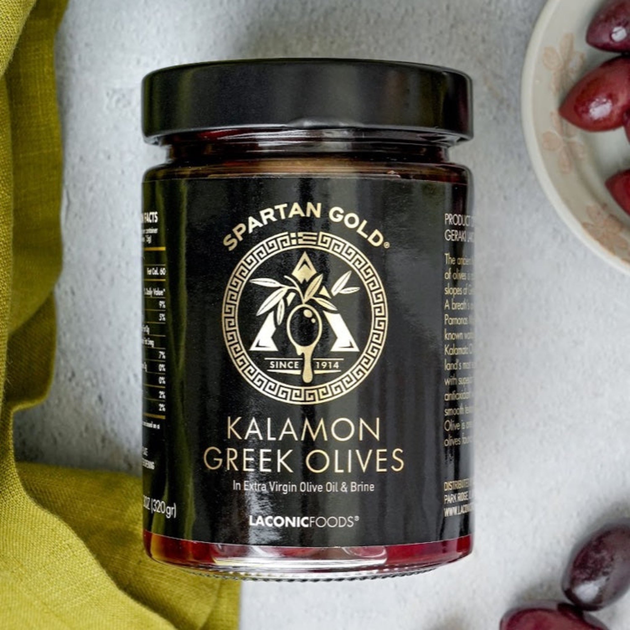 Laconic Foods Kalamon Greek Olives jar with green napkin and scattered olives