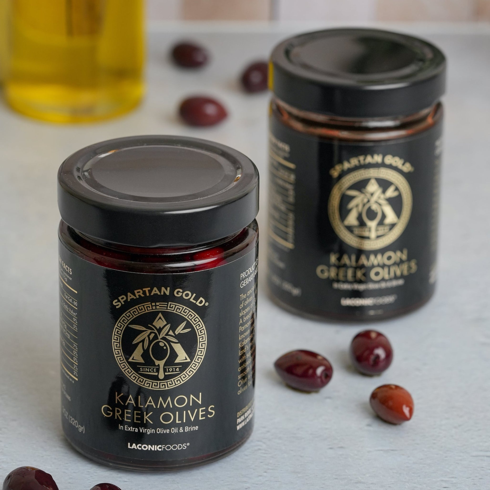 Two jars of Laconic Foods Kalamon Greek Olives with olives on kitchen counter