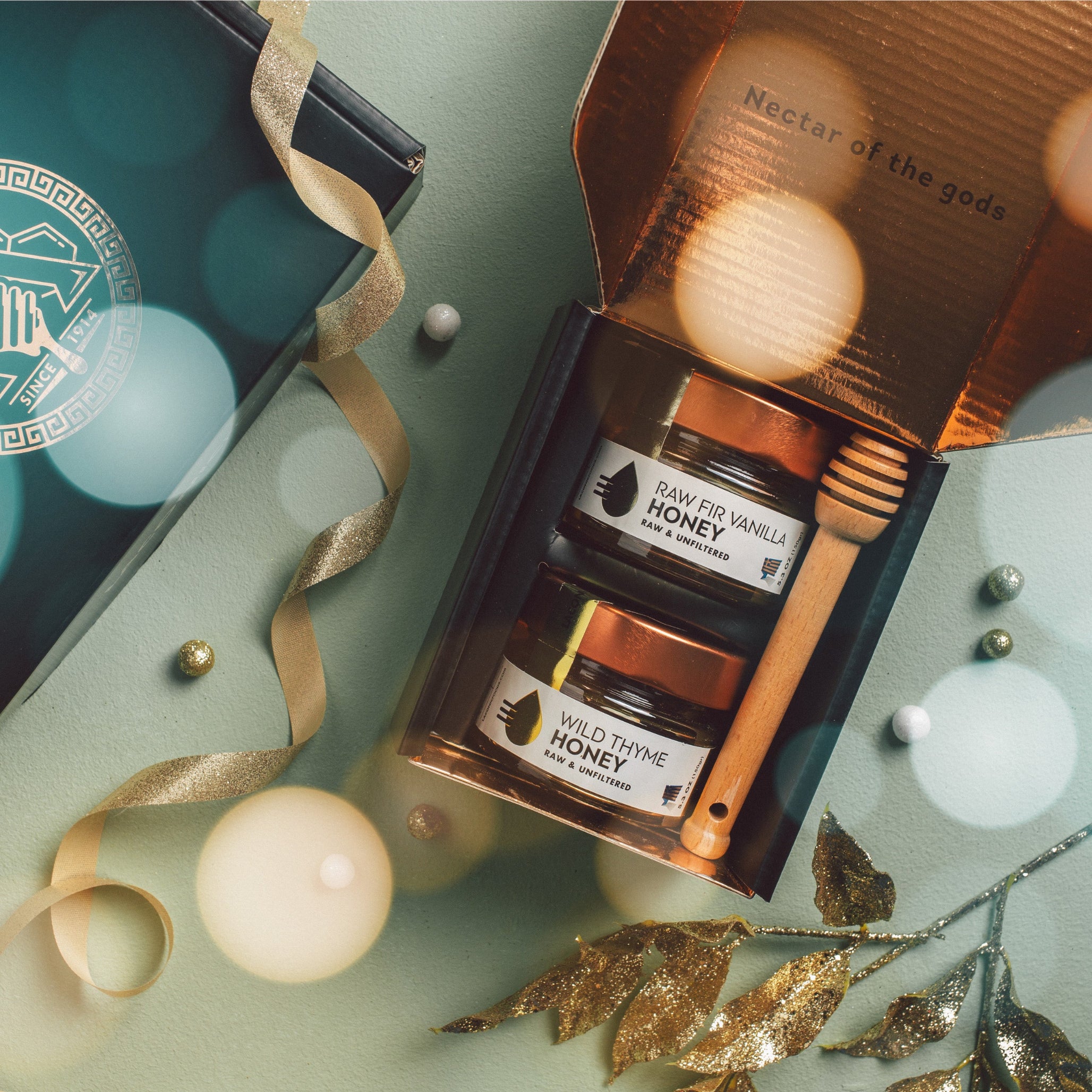 Greek honey gift set with Wild Thyme and Raw Fir Vanilla honey jars, festive holiday packaging, and wooden honey dipper.