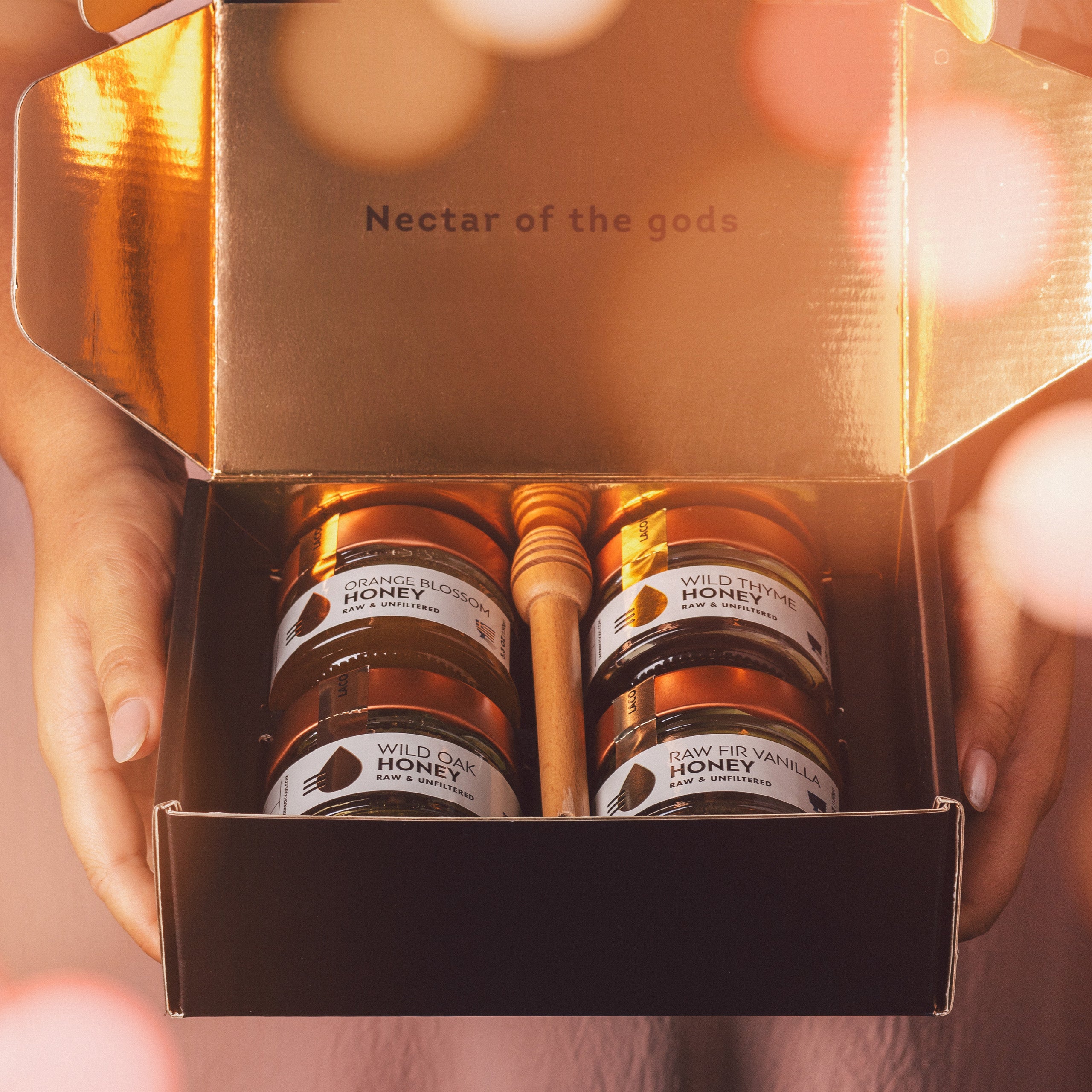 Premium Greek Honey Gift Set – 4 jars of raw unfiltered honey with festive holiday packaging and wooden dipper.
