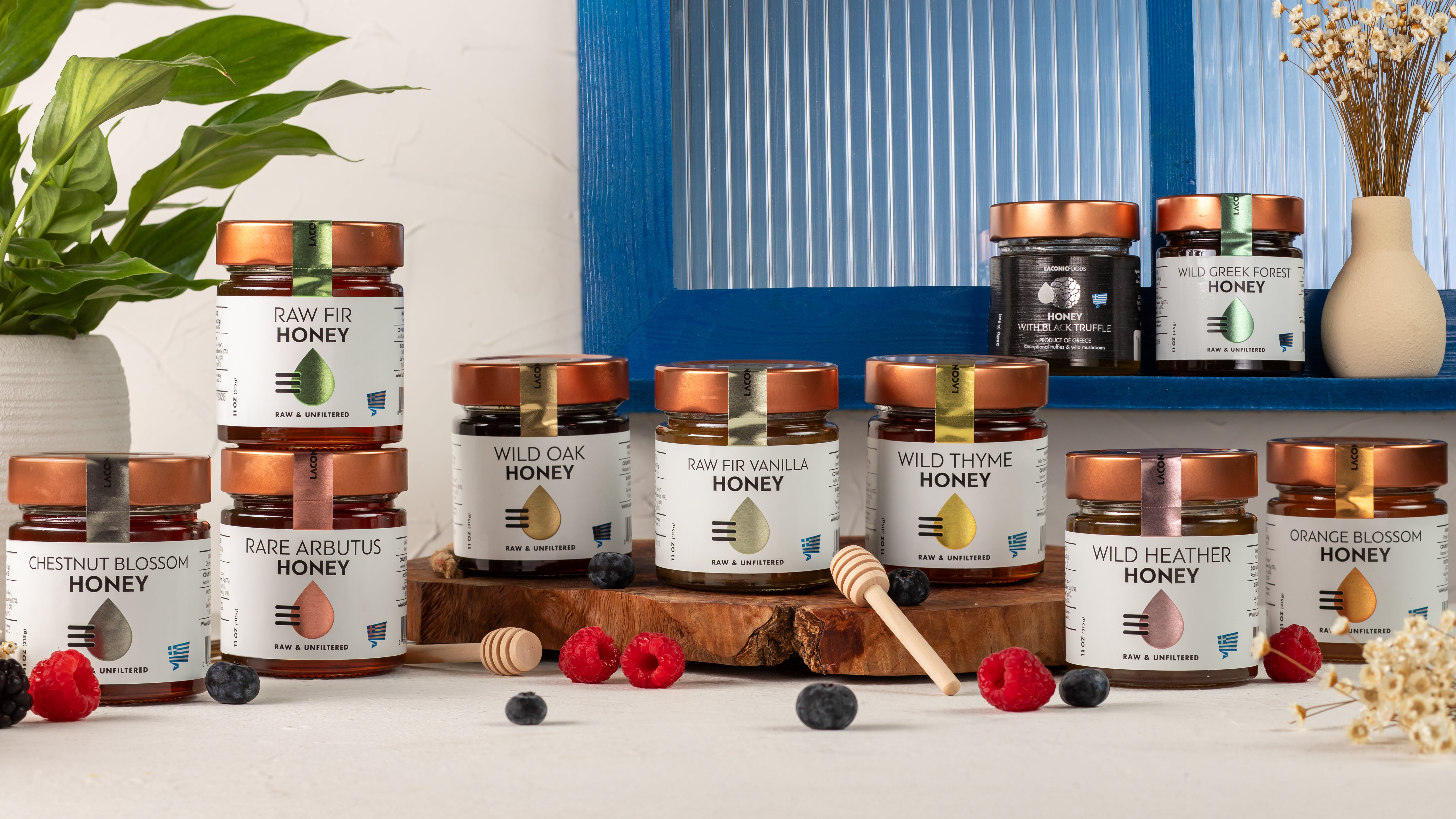 Group photo of Laconic Foods Greek honey collection including Raw Fir, Wild Oak, Wild Thyme, Wild Greek Forest, Raw Fir Vanilla, Wild Heather, Chestnut Blossom, Orange Blossom, and Rare Arbutus honeys.