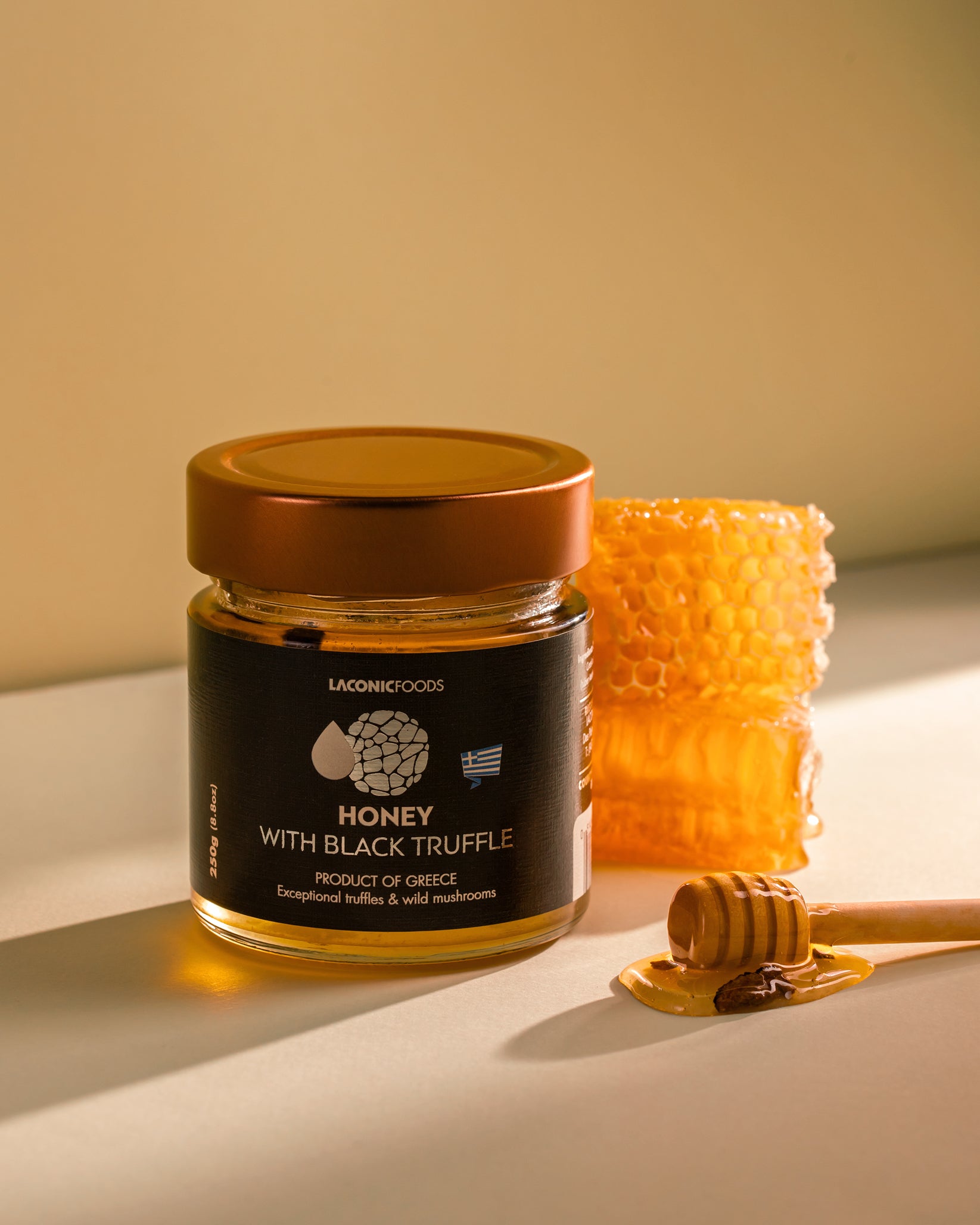 Laconic Foods Honey with Black Truffle 250g styled with honeycomb and wooden honey dipper – warm lighting highlights golden honey and truffle pieces.