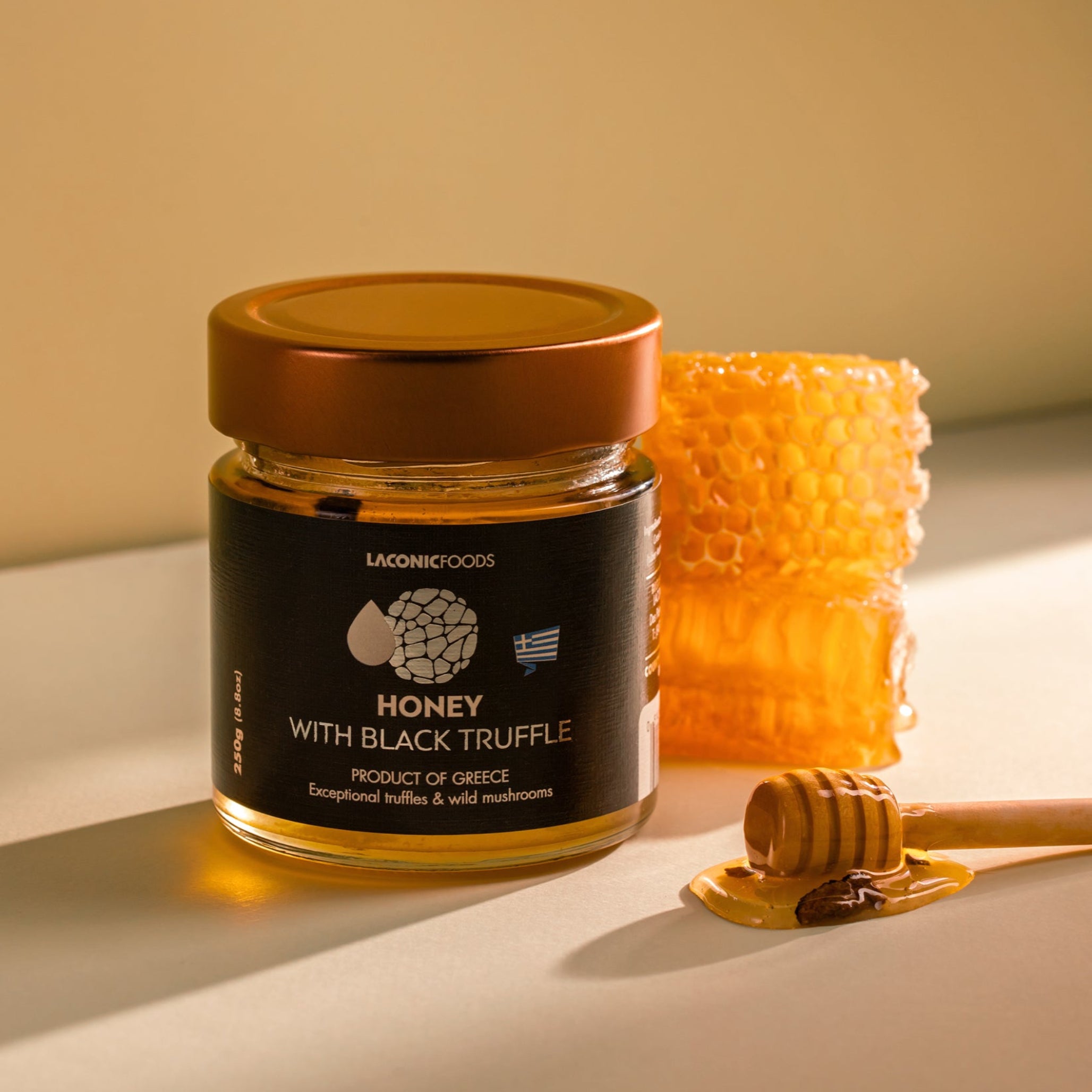 Laconic Foods Honey with Black Truffle 250g styled with honeycomb and wooden honey dipper – warm lighting highlights golden honey and truffle pieces.