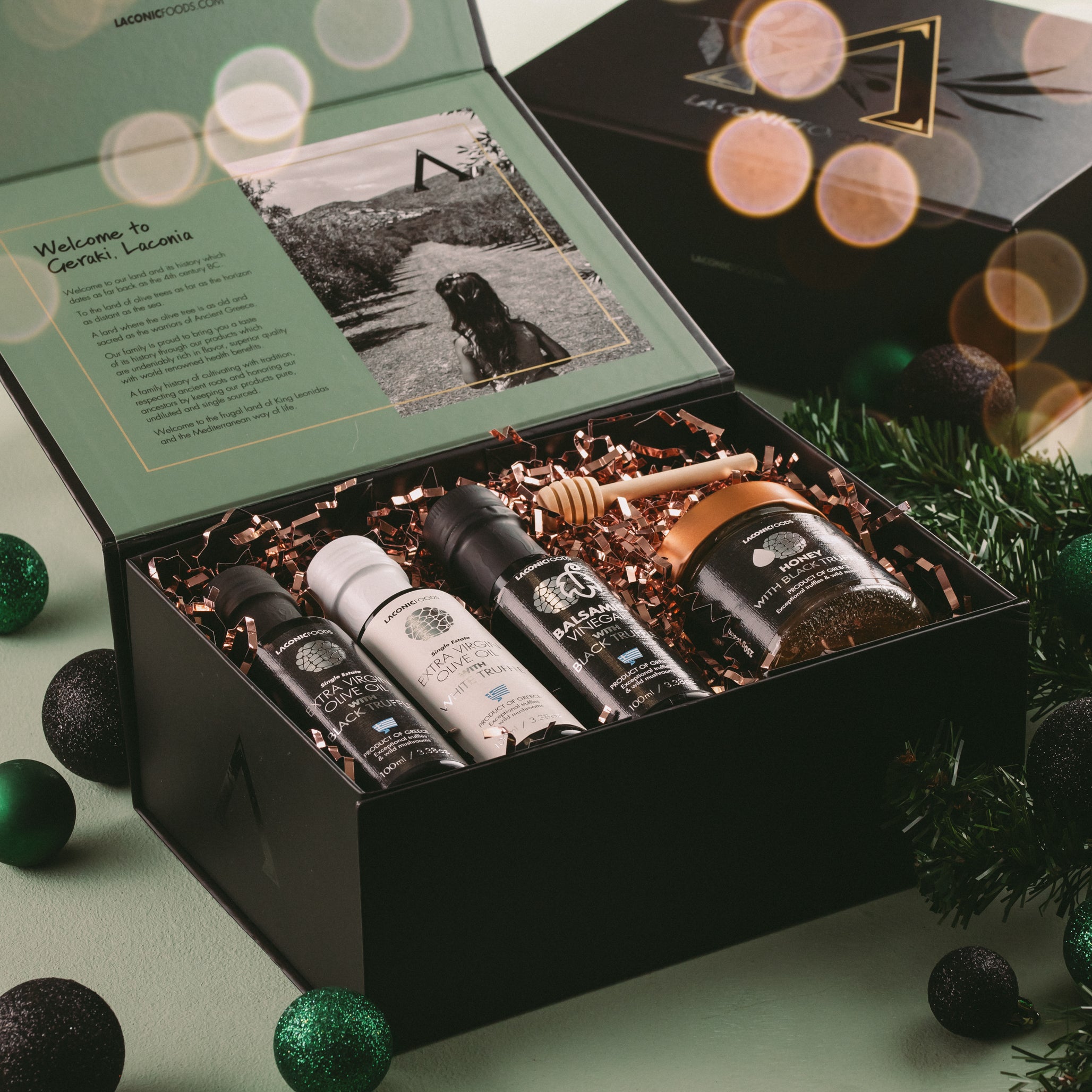 Laconic Foods premium gift box featuring extra virgin olive oil, white truffle olive oil, black truffle balsamic vinegar, and honey with black truffle in festive holiday packaging.