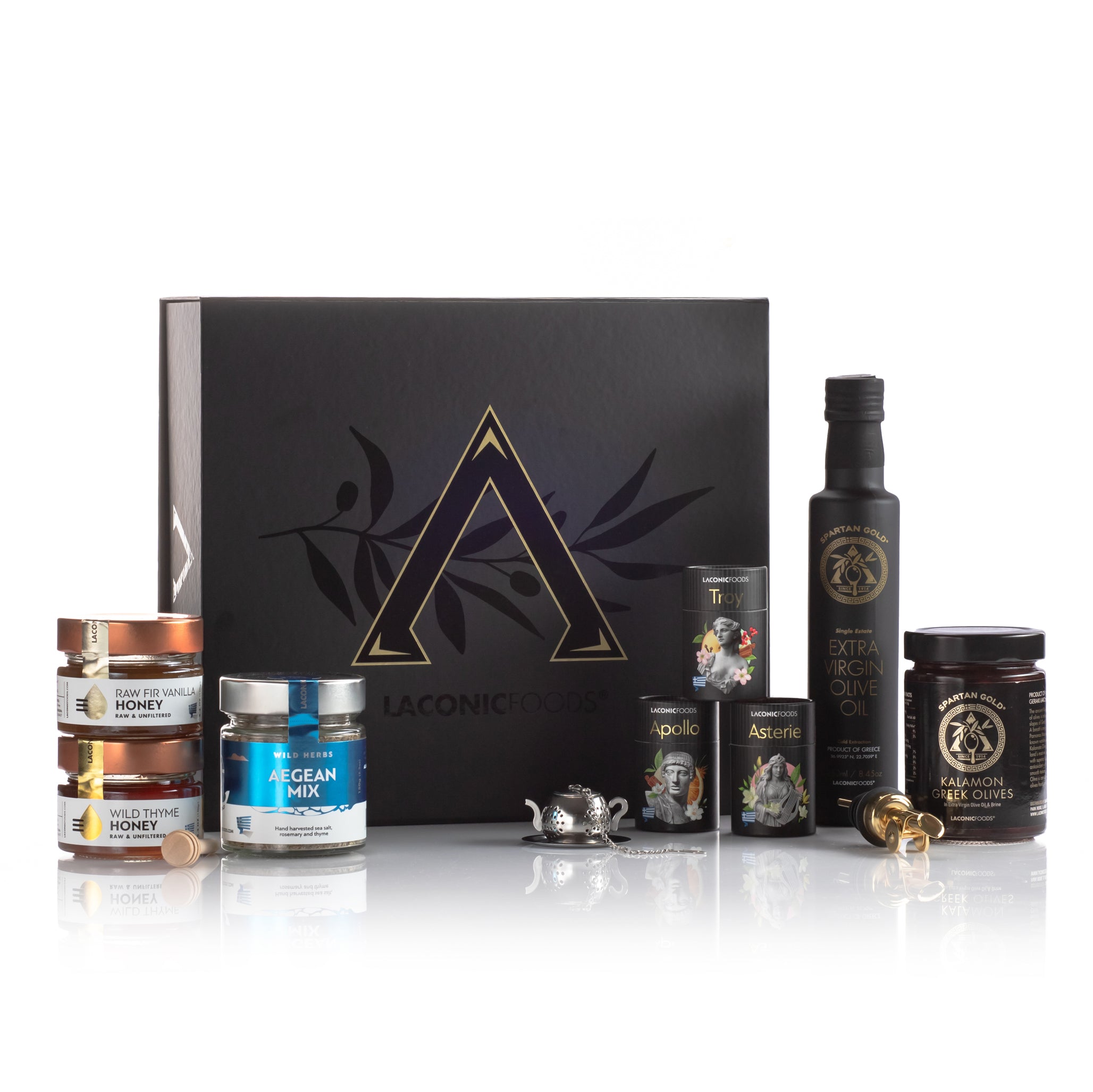 Complete product display of the Laconic Foods Premium Greek Gift Box showing all items outside the box including EVOO, olives, honeys, Aegean spice mix, mini teas, honey dipper, and tea accessories.