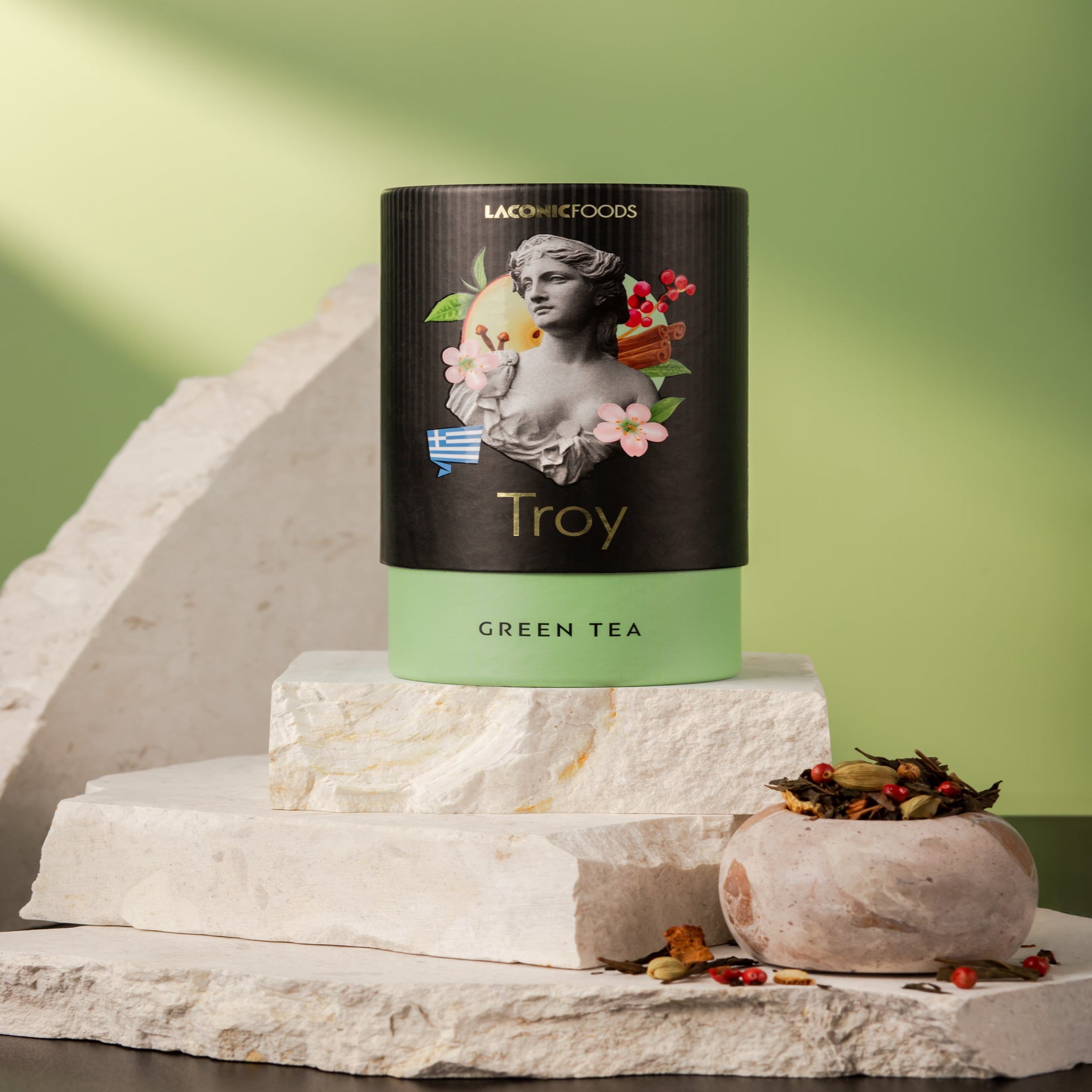 Front view of Laconic Foods Troy Green Tea canister – premium Greek loose leaf green tea styled on marble stones with green background.