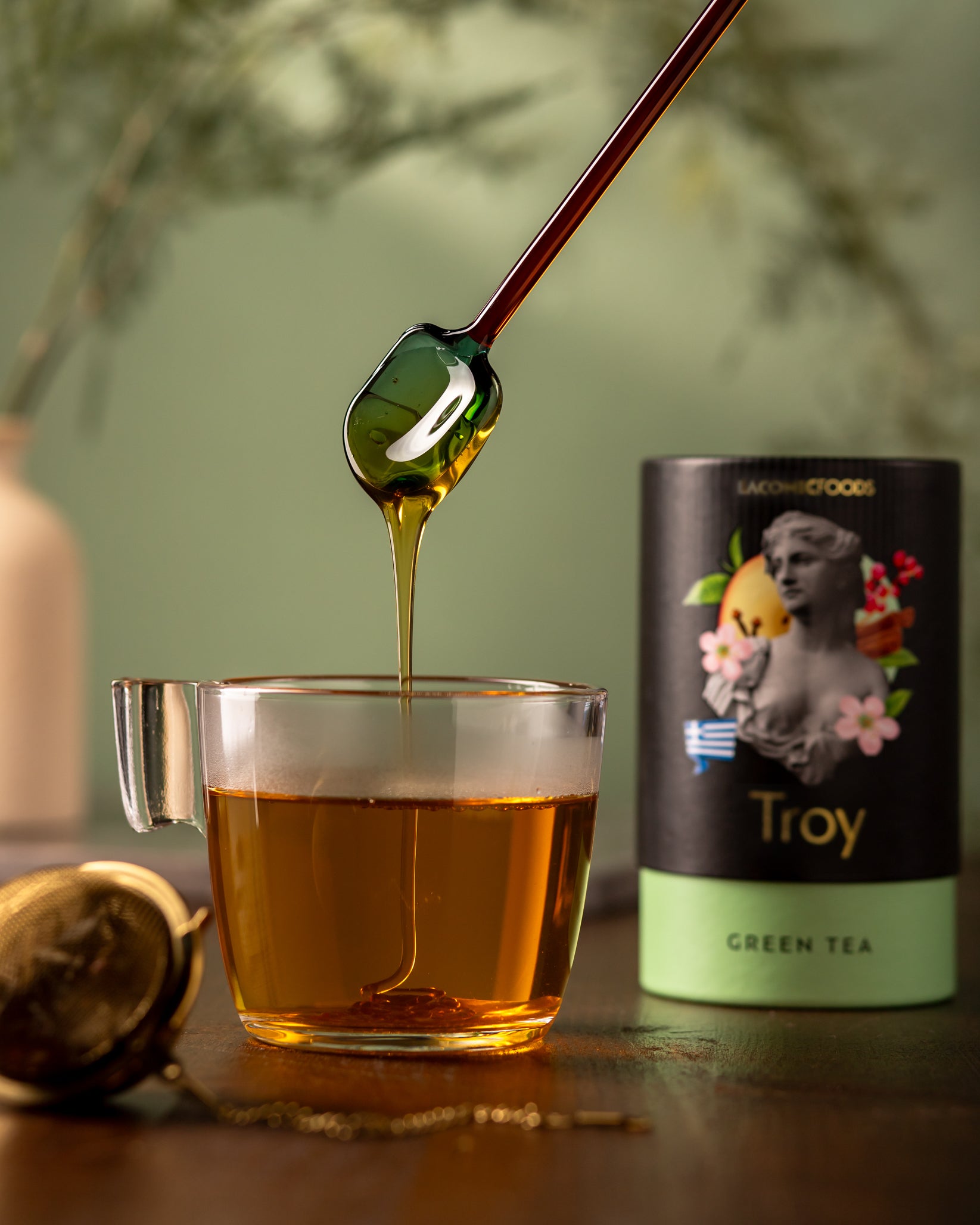 Laconic Foods Troy Green Tea brewed in glass cup with honey drizzle – aromatic Greek green tea with cardamom, orange, and spice notes.
