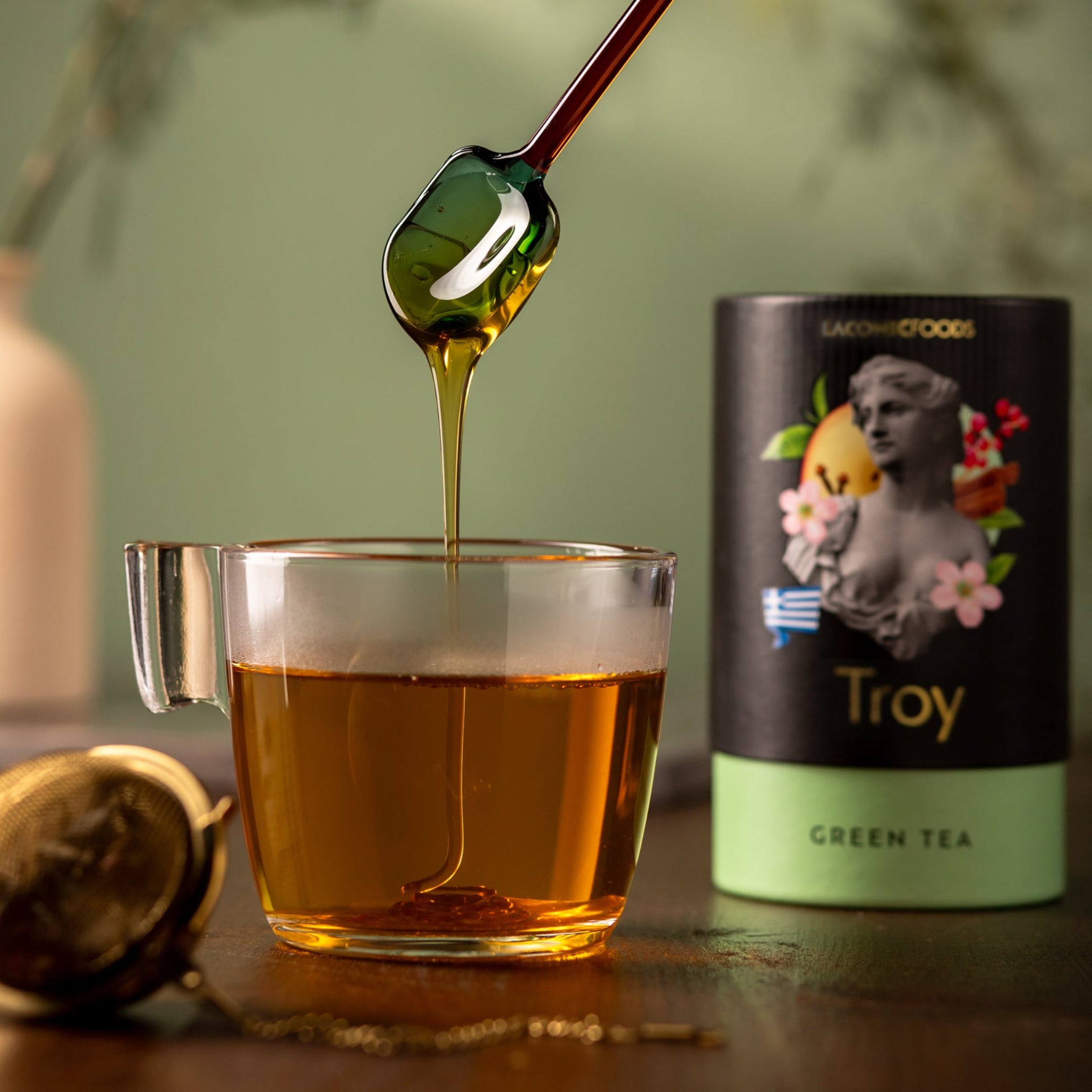 Laconic Foods Troy Green Tea brewed in glass cup with honey drizzle – aromatic Greek green tea with cardamom, orange, and spice notes.