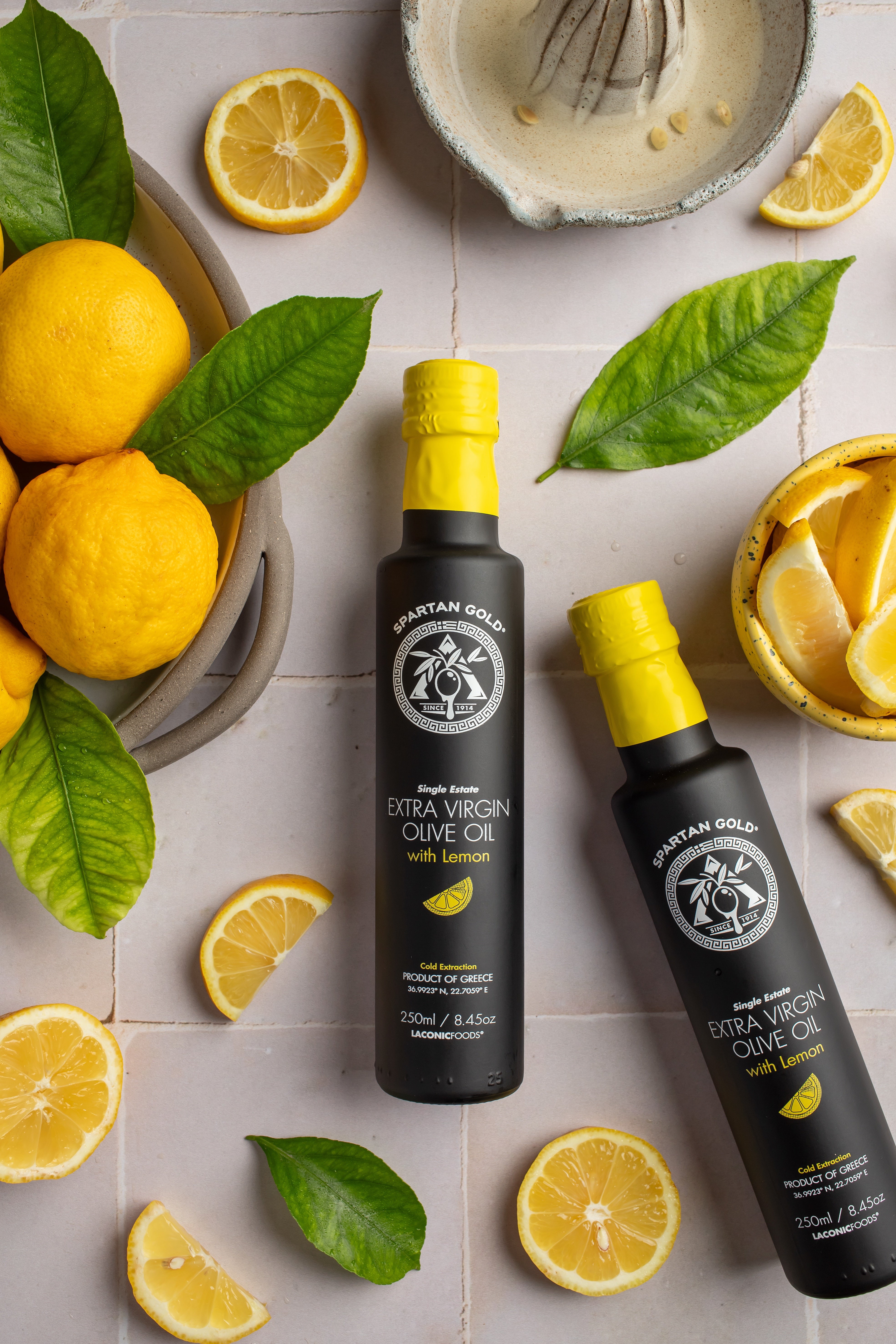 Flat lay of Lemon Infused Extra Virgin Olive Oil bottles with fresh lemons and leaves