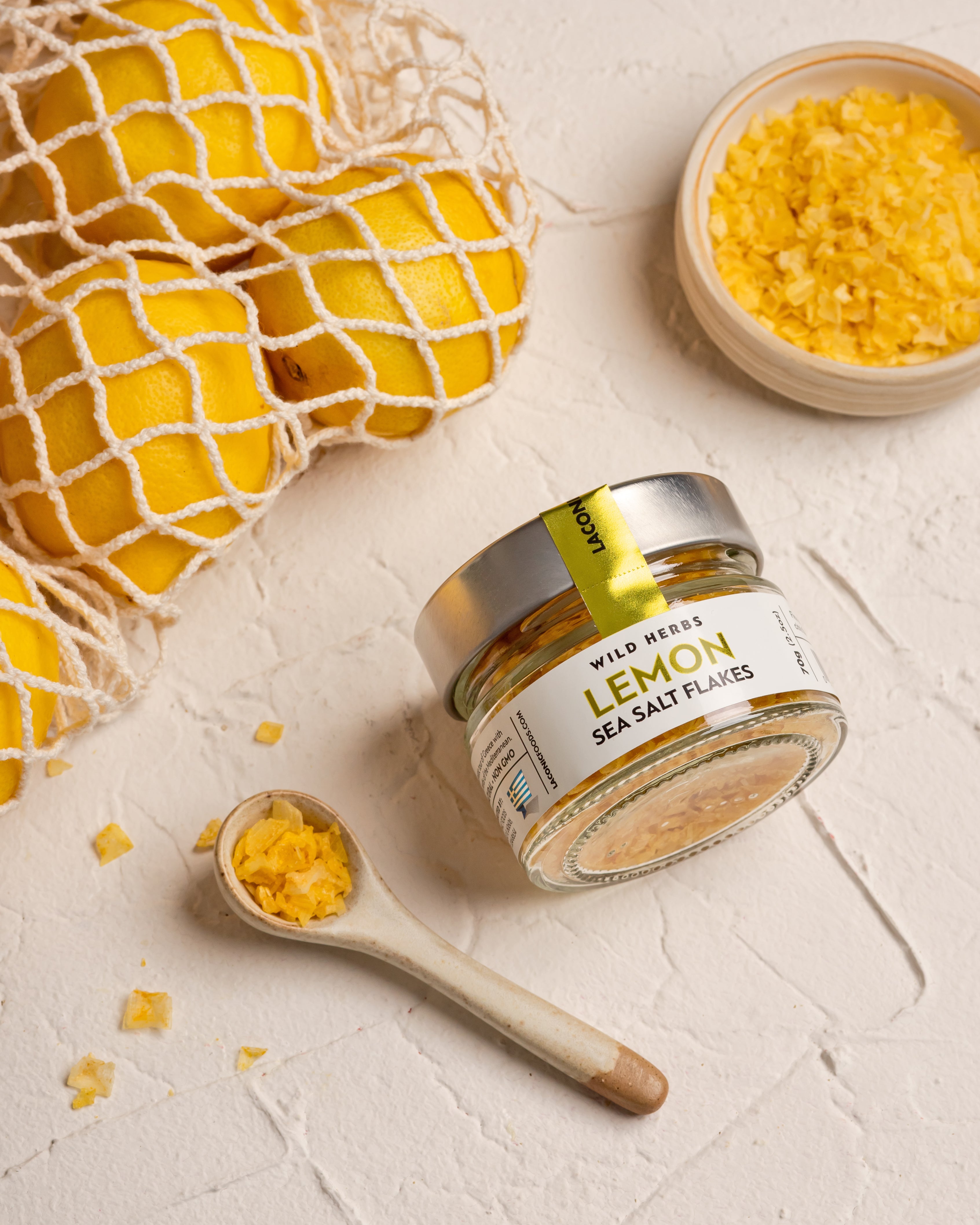 Laconic Foods Lemon Sea Salt Flakes with whole lemons and a wooden spoon of salt