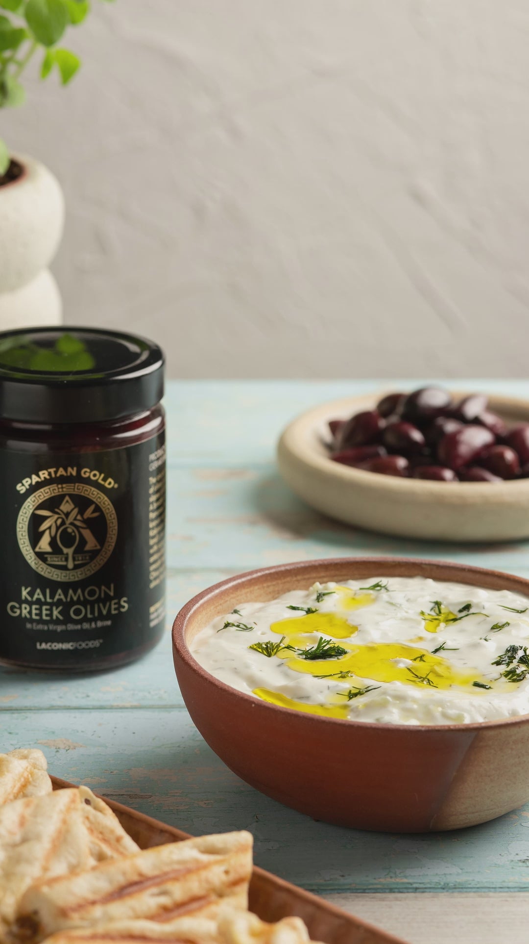 Video of Kalamon Greek olive being placed into a bowl of creamy tzatziki.
