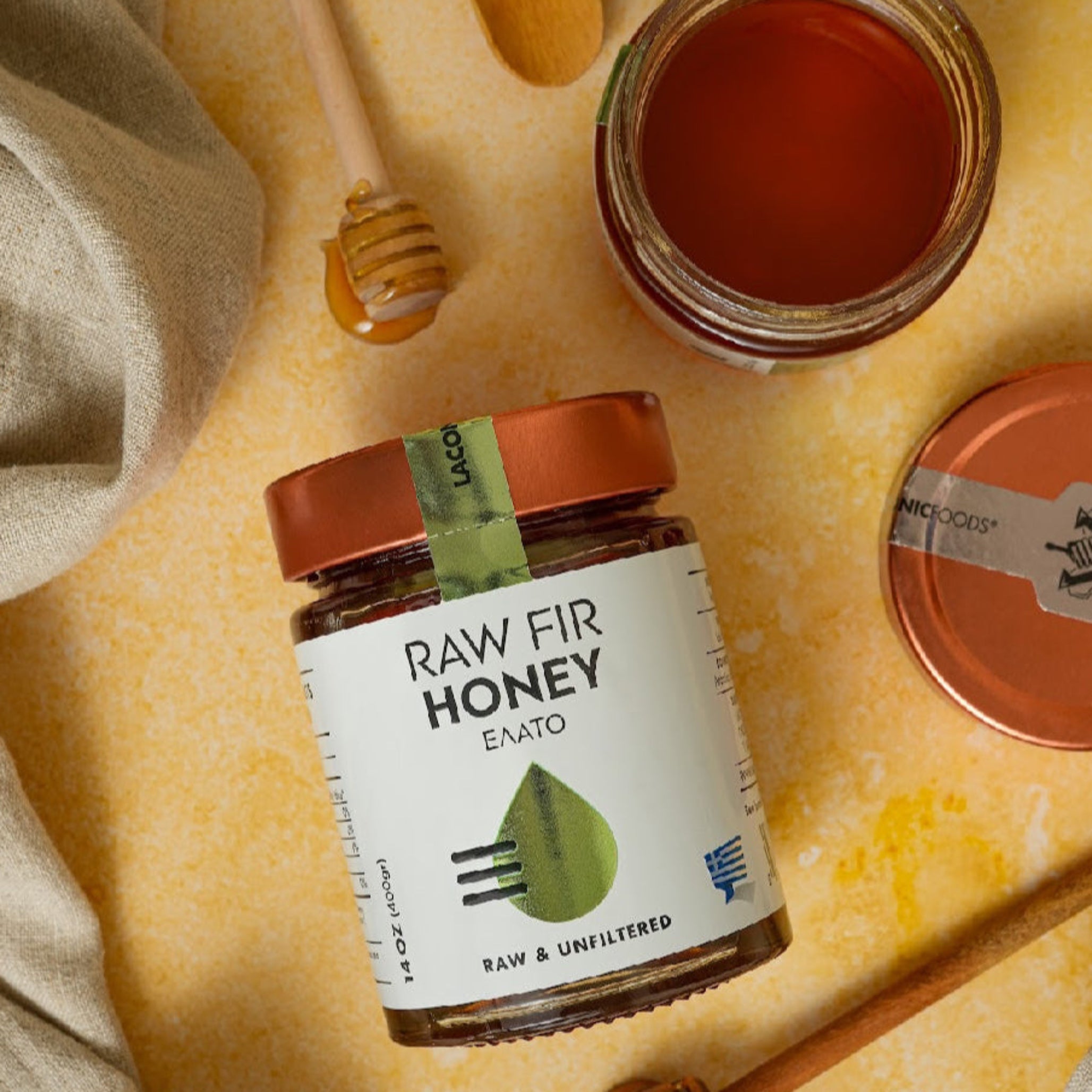 Greek Raw Fir Honey with wooden dipper and open jar on rustic background