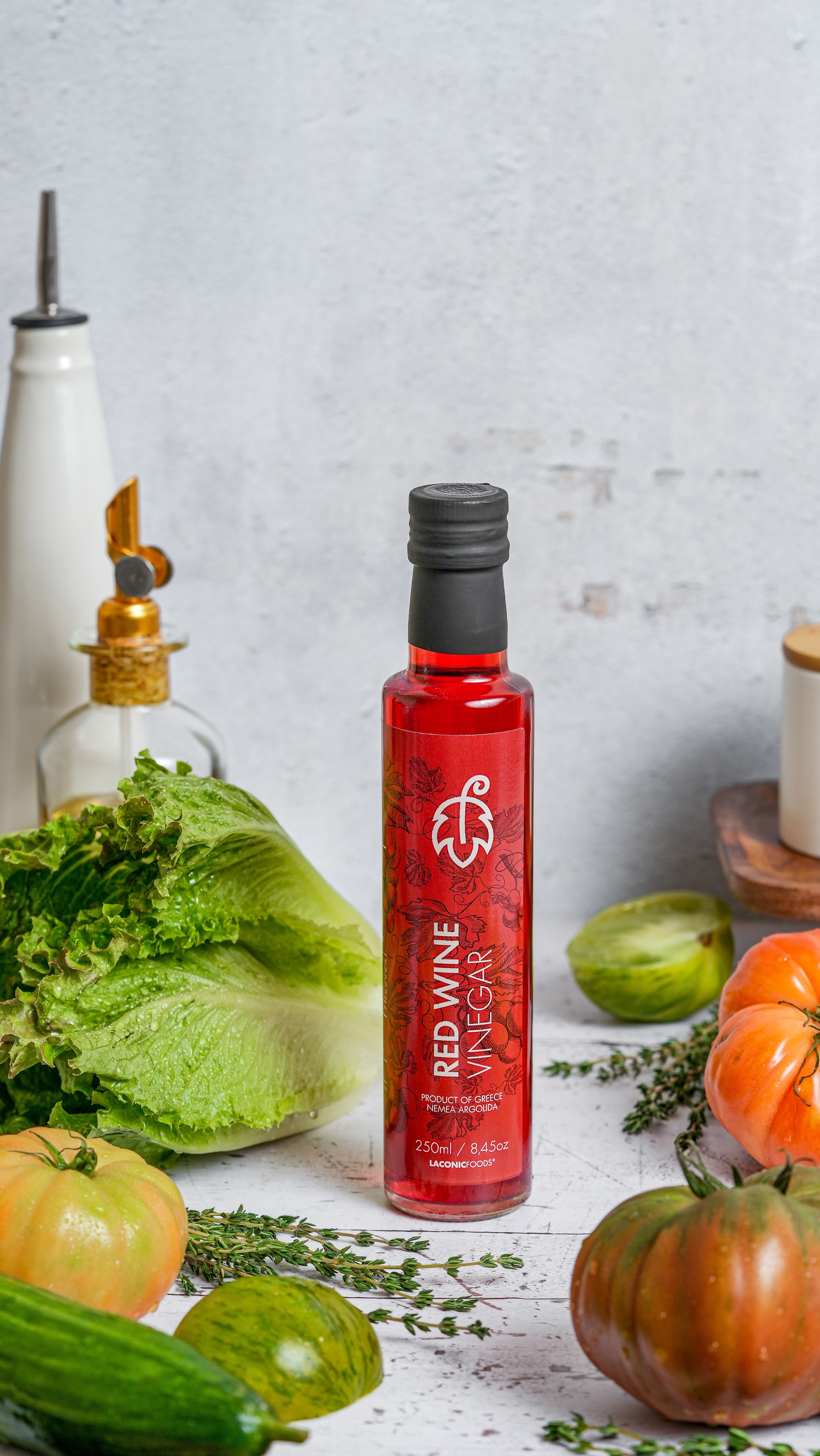 250ml bottle of Greek Red Wine Vinegar from Nemea by Laconic Foods surrounded by fresh vegetables