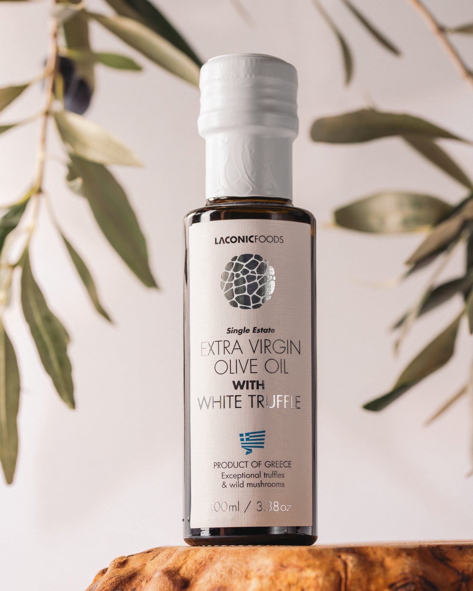 Laconic Foods Extra Virgin Olive Oil with White Truffle shown against a light background with olive branches.