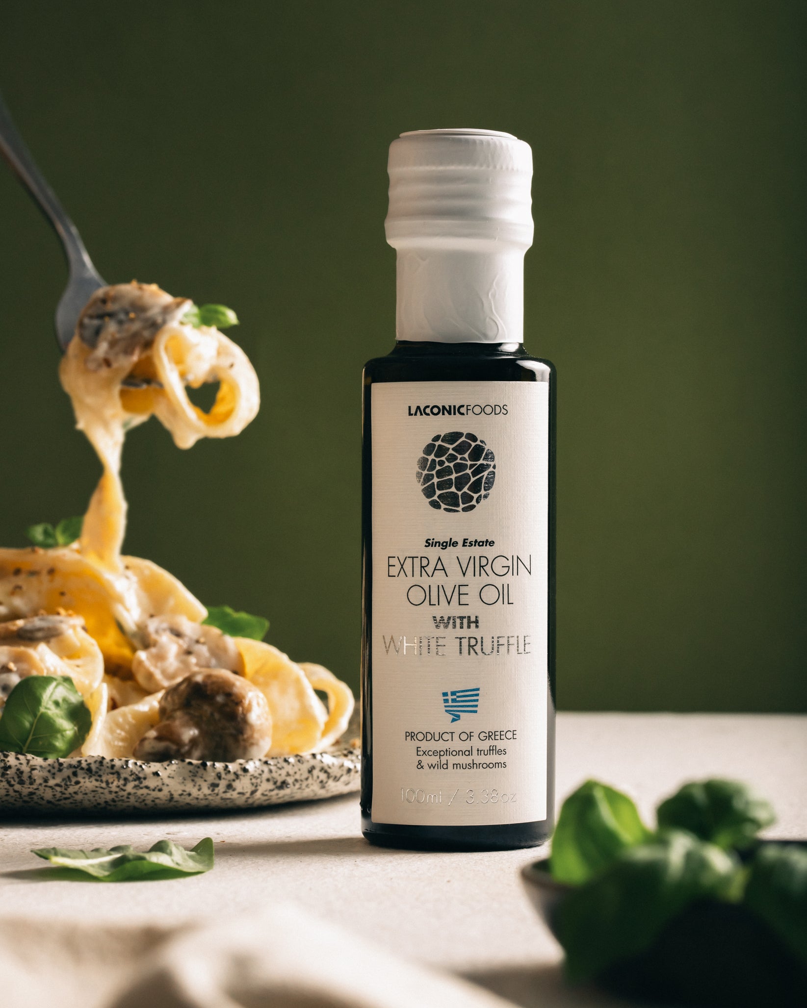 Laconic Foods Extra Virgin Olive Oil with White Truffle next to creamy tagliatelle pasta being lifted with a fork.